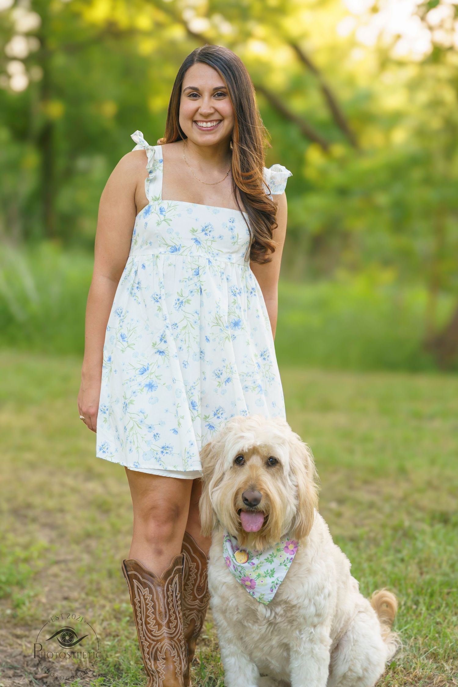 Woman standing outdoors in a floral dress with her dog during a natural light portrait session.