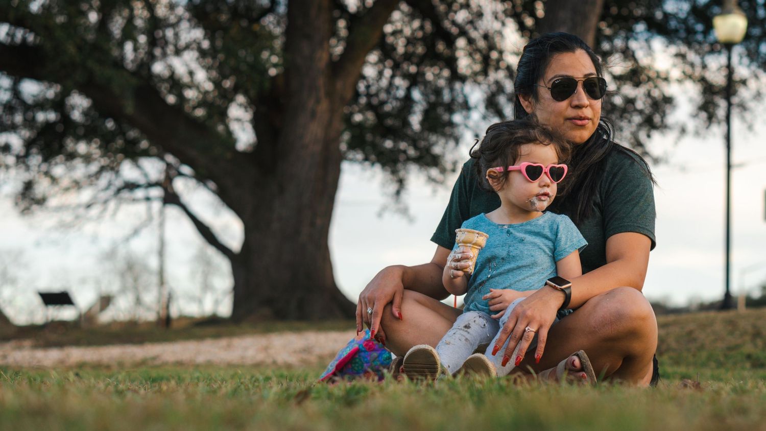 Family relaxing together on grass during a sunny afternoon in the park.