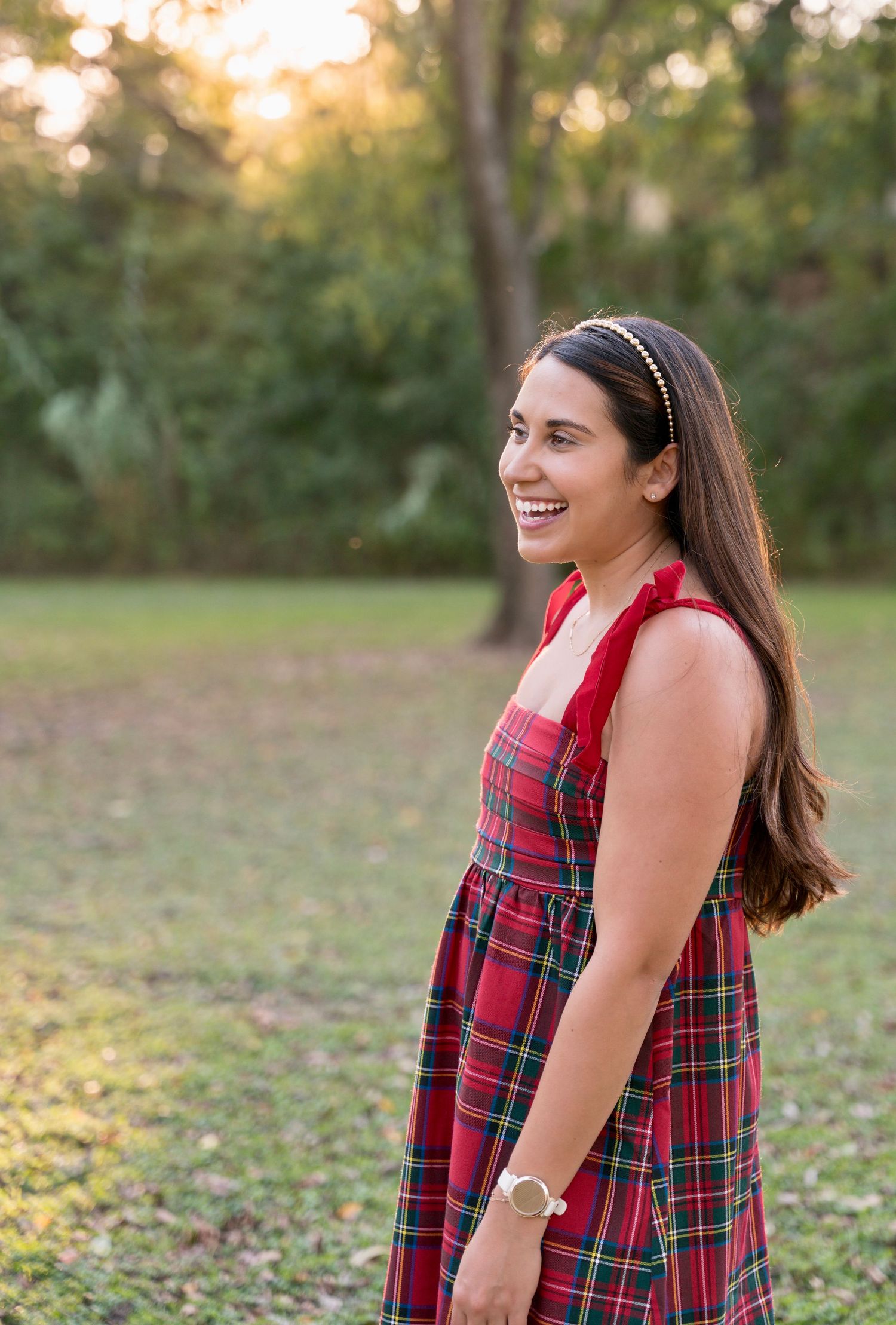 Outdoor lifestyle portrait of a woman wearing a red plaid dress, captured in soft natural light.