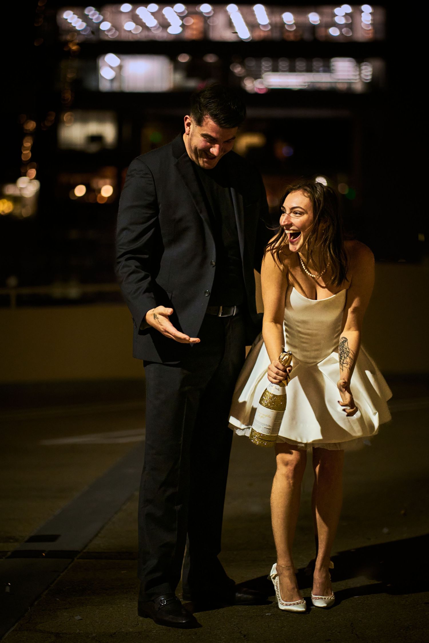 Couple shares romantic moment during nighttime photo session in city setting.