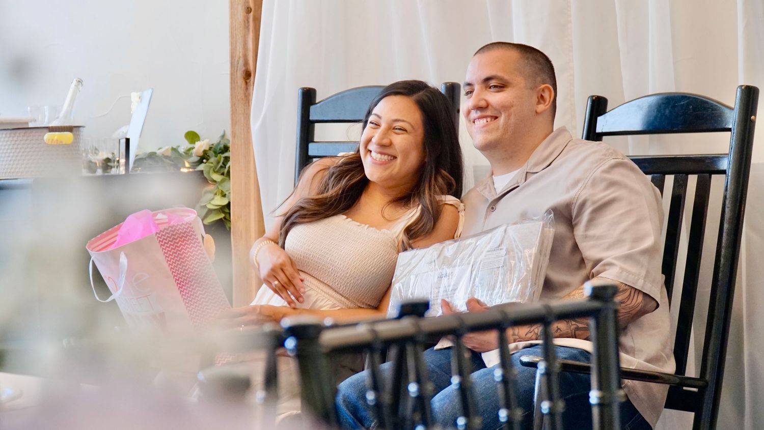 A happy couple sits together at a cafe table, smiling and enjoying a relaxed moment together.