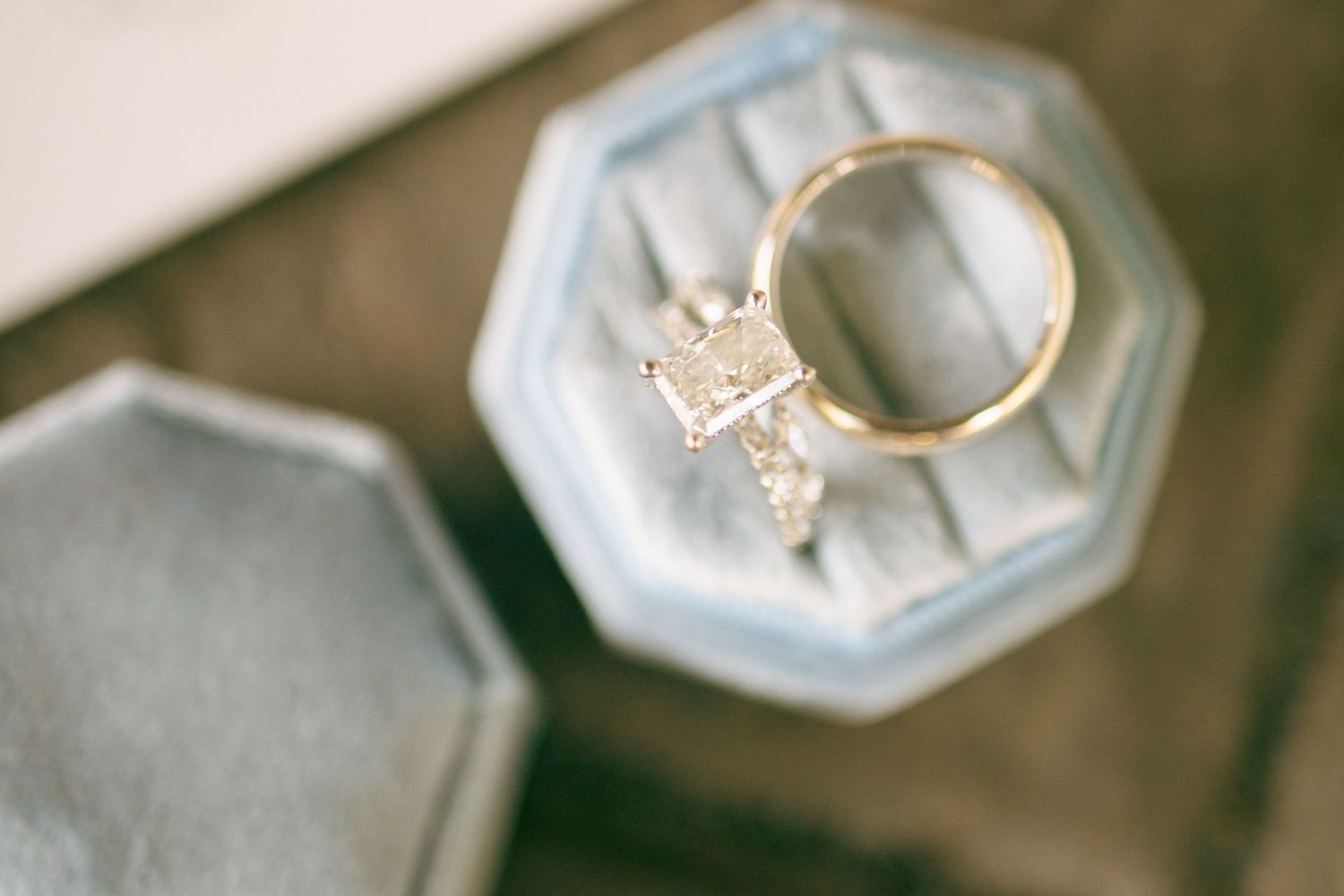Diamond engagement ring and gold wedding band displayed in a light blue velvet octagonal ring box.