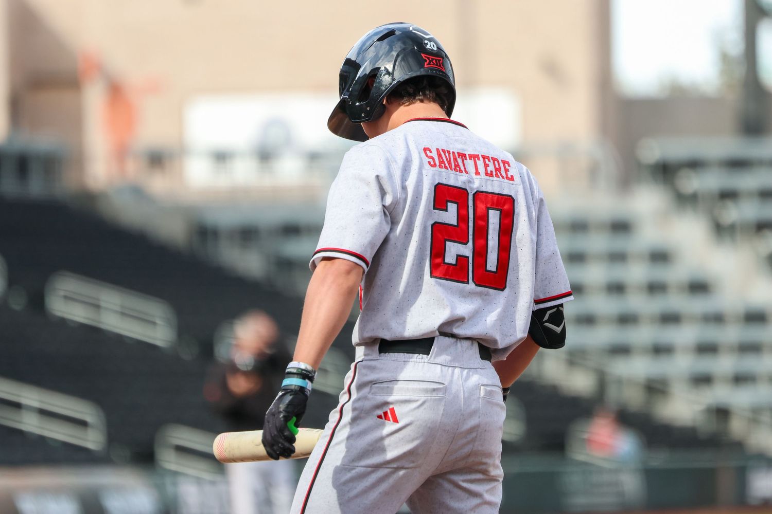 A baseball player in a white uniform with number 20 stands at bat during a game.