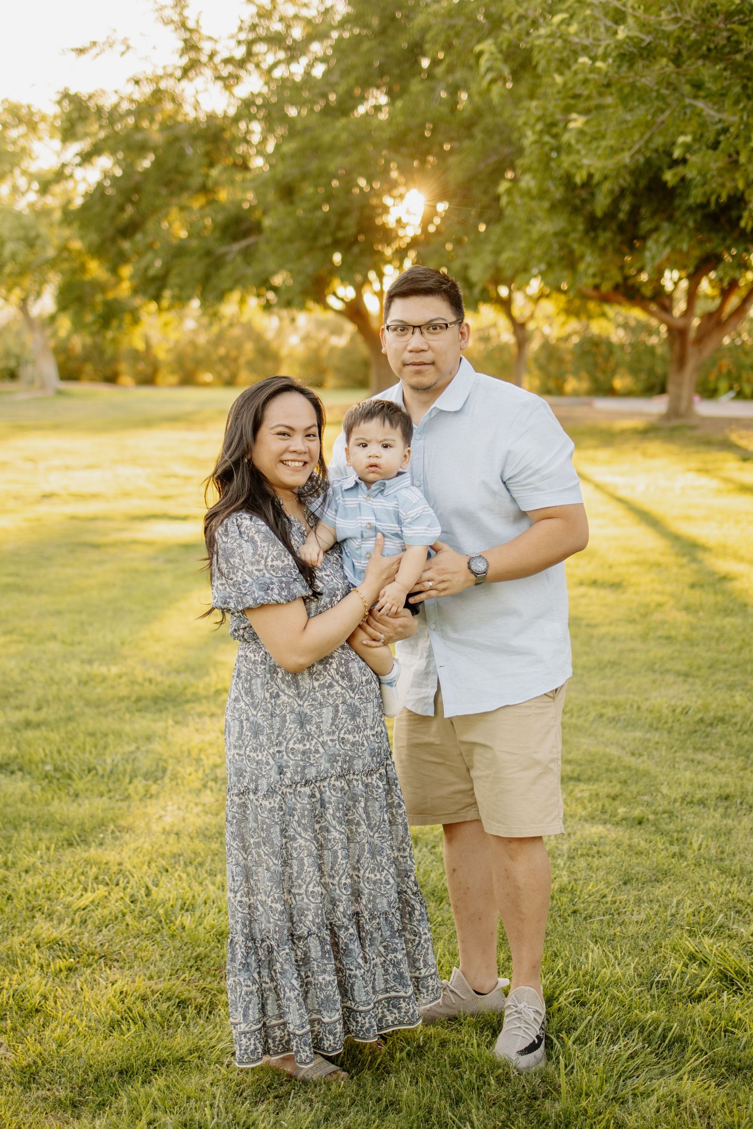 Family posing together in park during golden hour sunset.