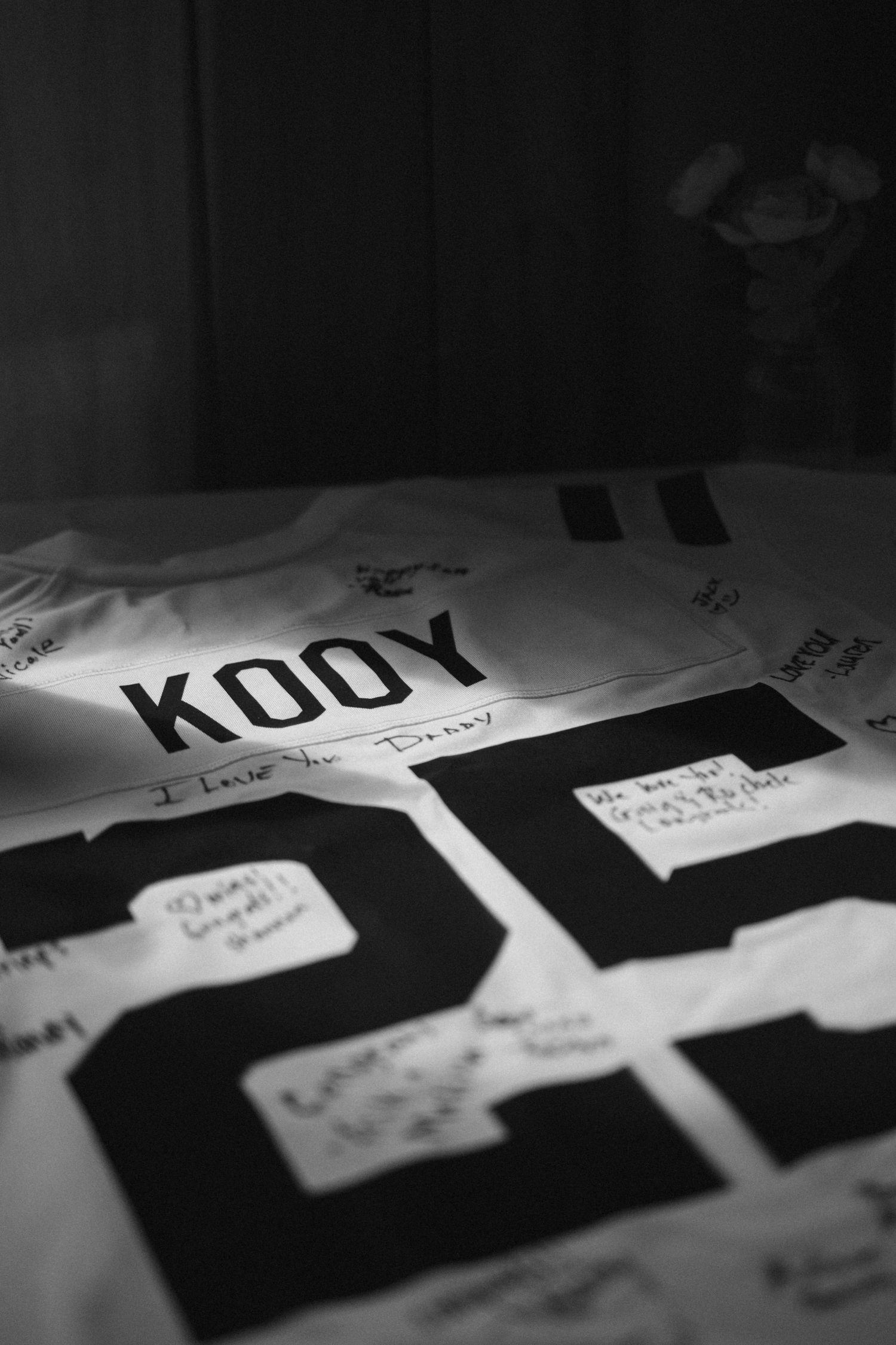 Black and white close-up of a signed sports jersey with number 25 and name KOOY at a wedding reception.