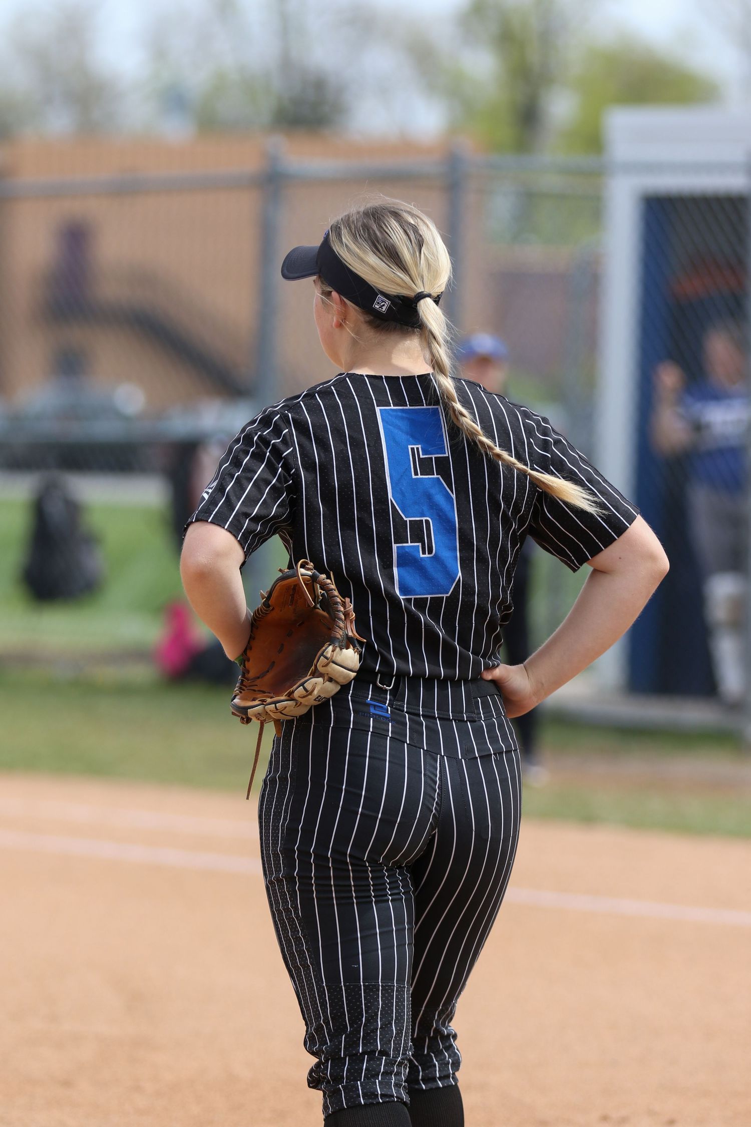 Baseball player wearing pinstriped uniform number 5 stands ready on field with glove for defensive play.
