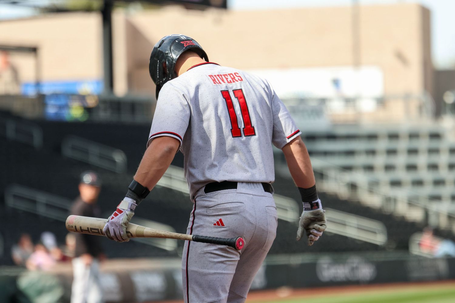 Baseball player wearing jersey number 11 stands at bat during game at outdoor stadium.