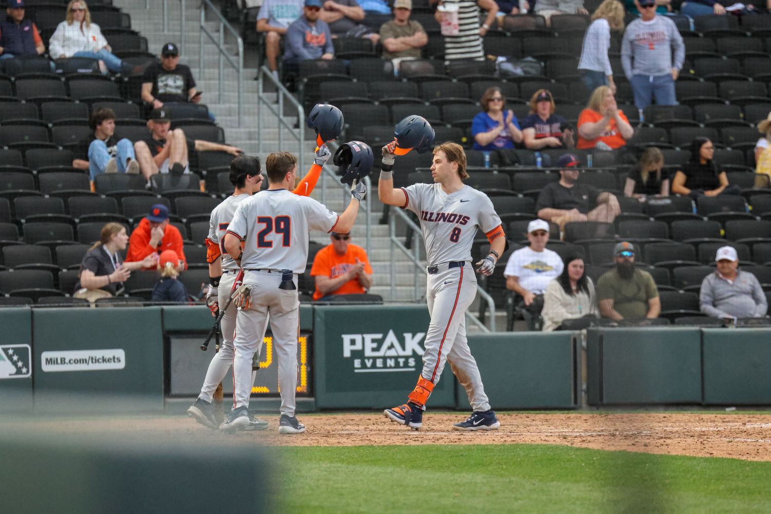 Baseball players from opposing teams interact at home plate during a professional baseball game with spectators in the stands.