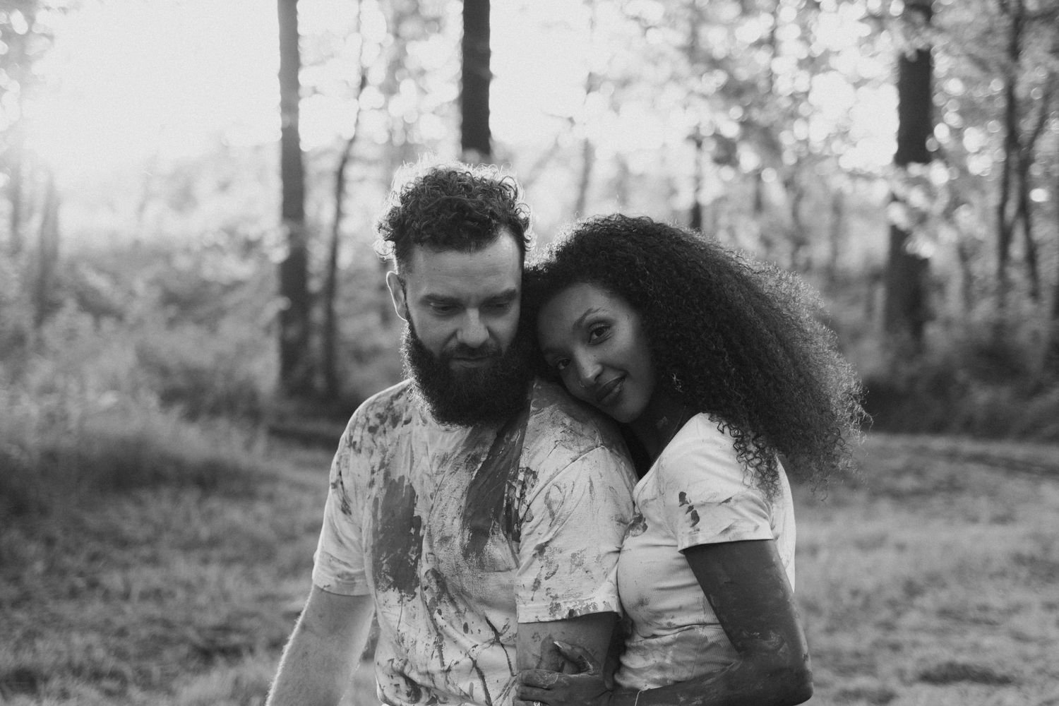 Candid black and white photo series of a couple embracing outdoors in a natural setting.