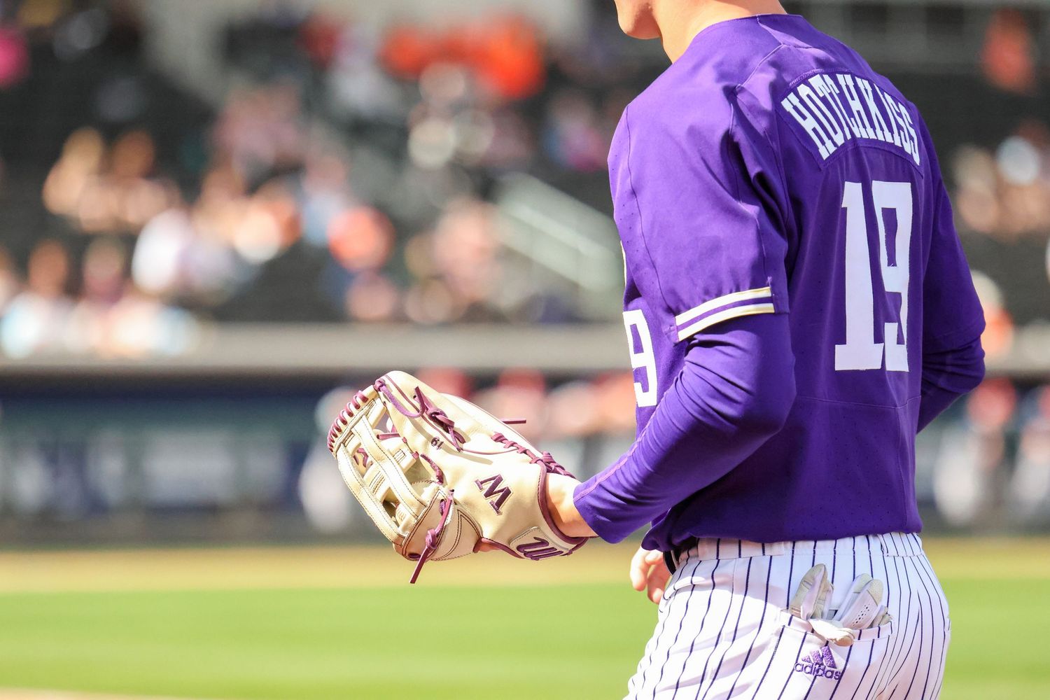 Baseball player wearing purple jersey number 17 stands ready on field during game.