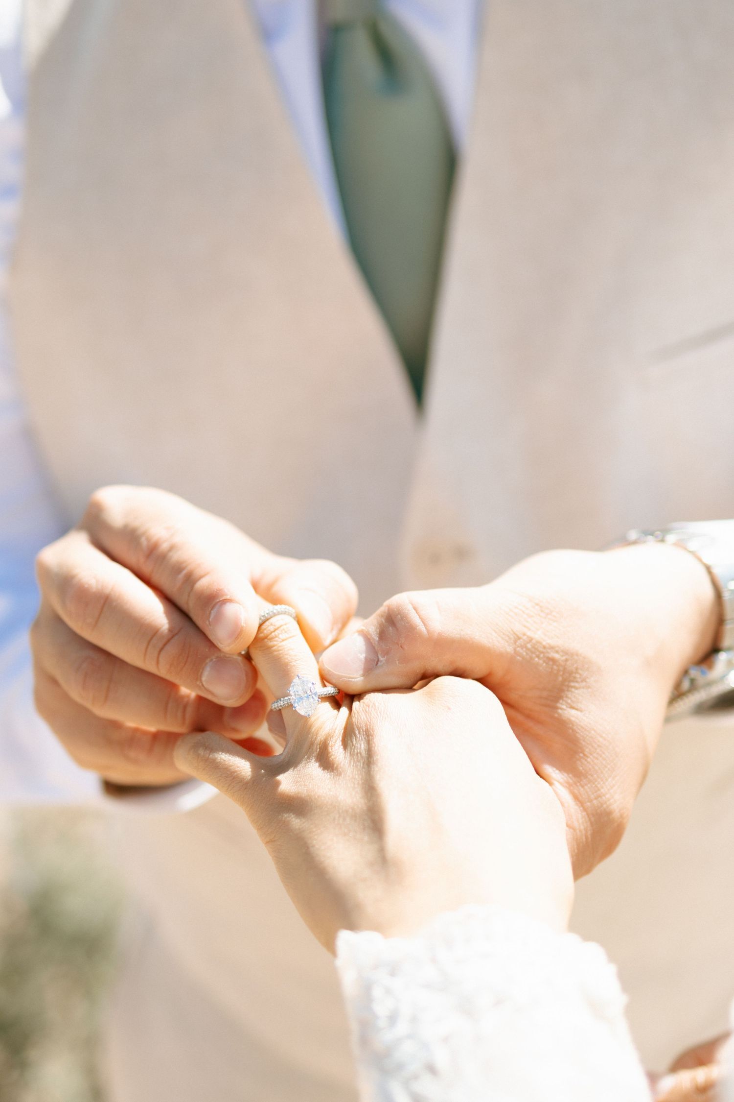 Close-up shot of hands exchanging wedding rings during an outdoor ceremony.