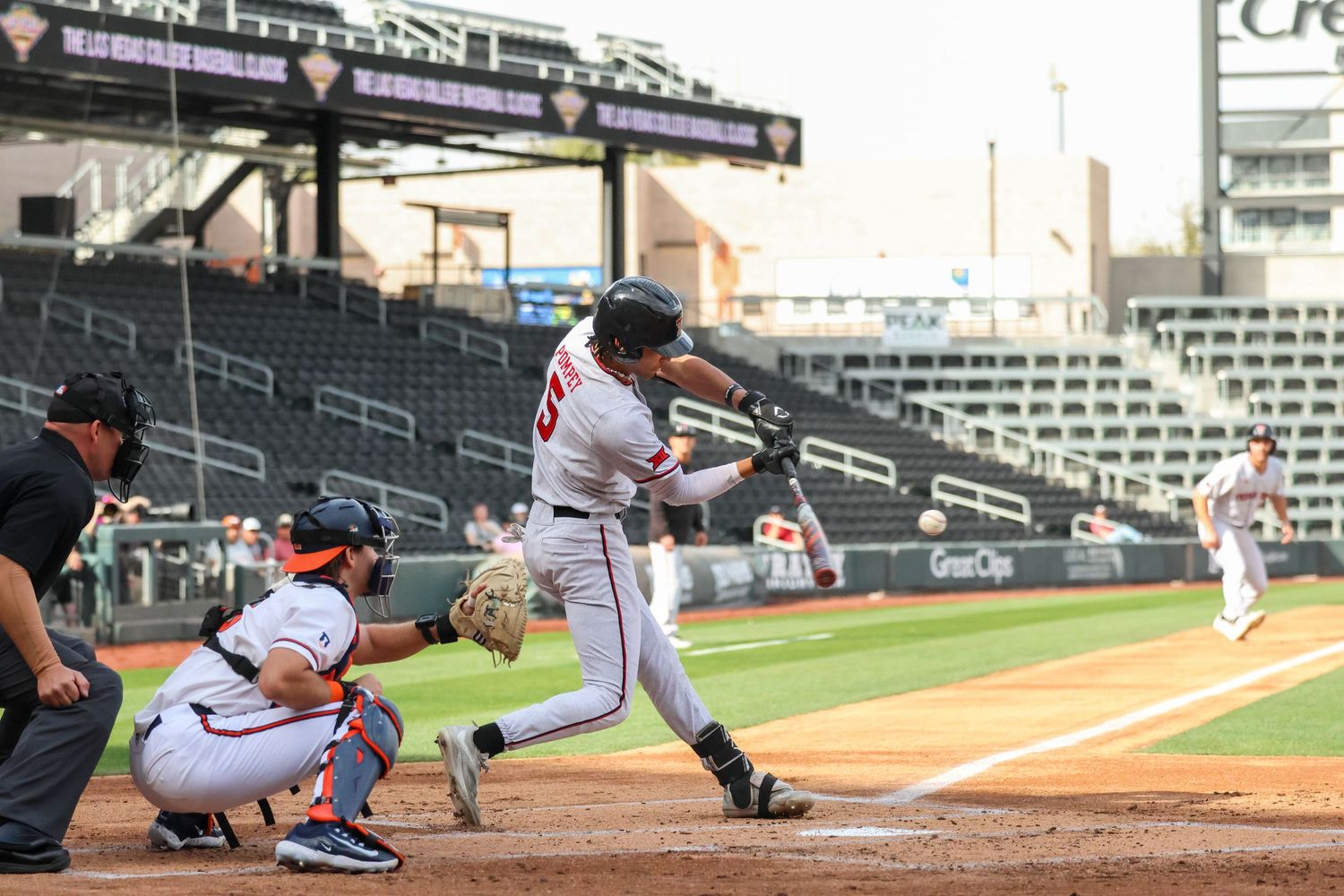 Baseball player follows through on swing at bat while catcher crouches during professional game.
