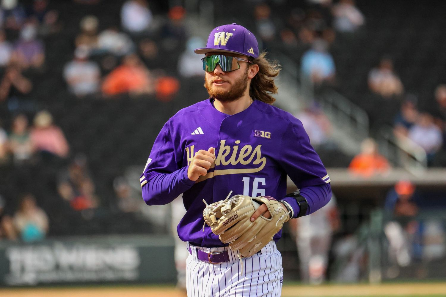 Baseball player in purple Colorado Rockies uniform and cap running across field during night game.