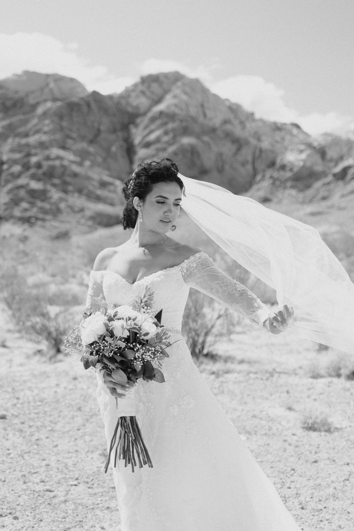 A bride in a flowing white dress poses dramatically against a desert mountain backdrop in a series of artistic shots.