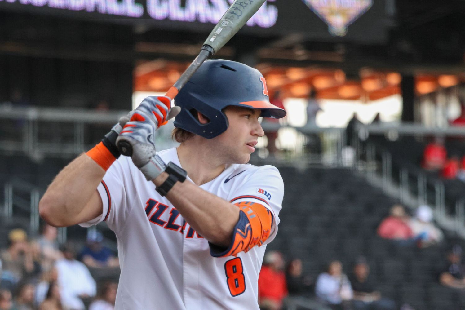 Baseball player in white uniform with black helmet and orange trim at bat during a game at a stadium.