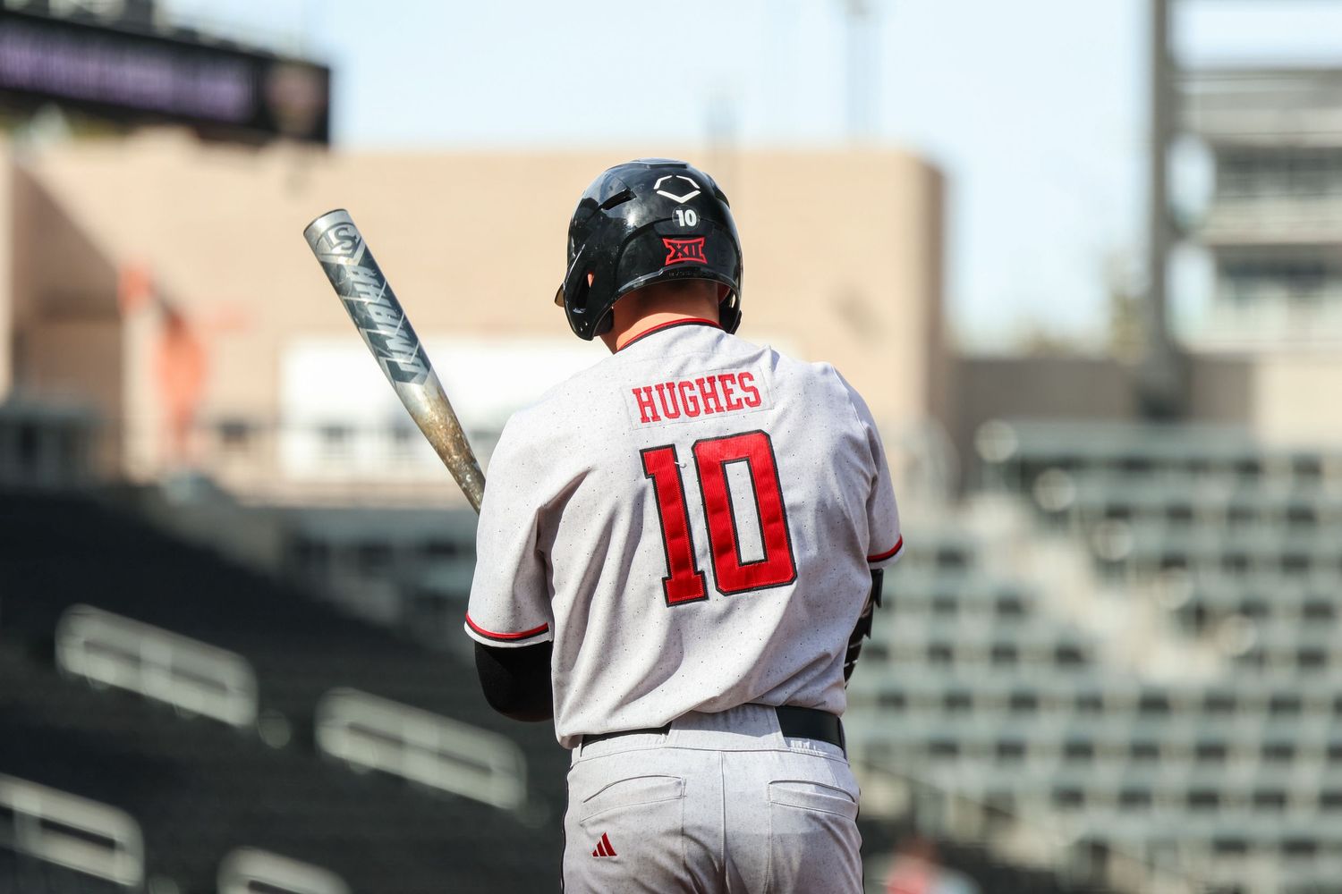 Baseball player wearing jersey number 10 stands at bat in stadium during daytime game.