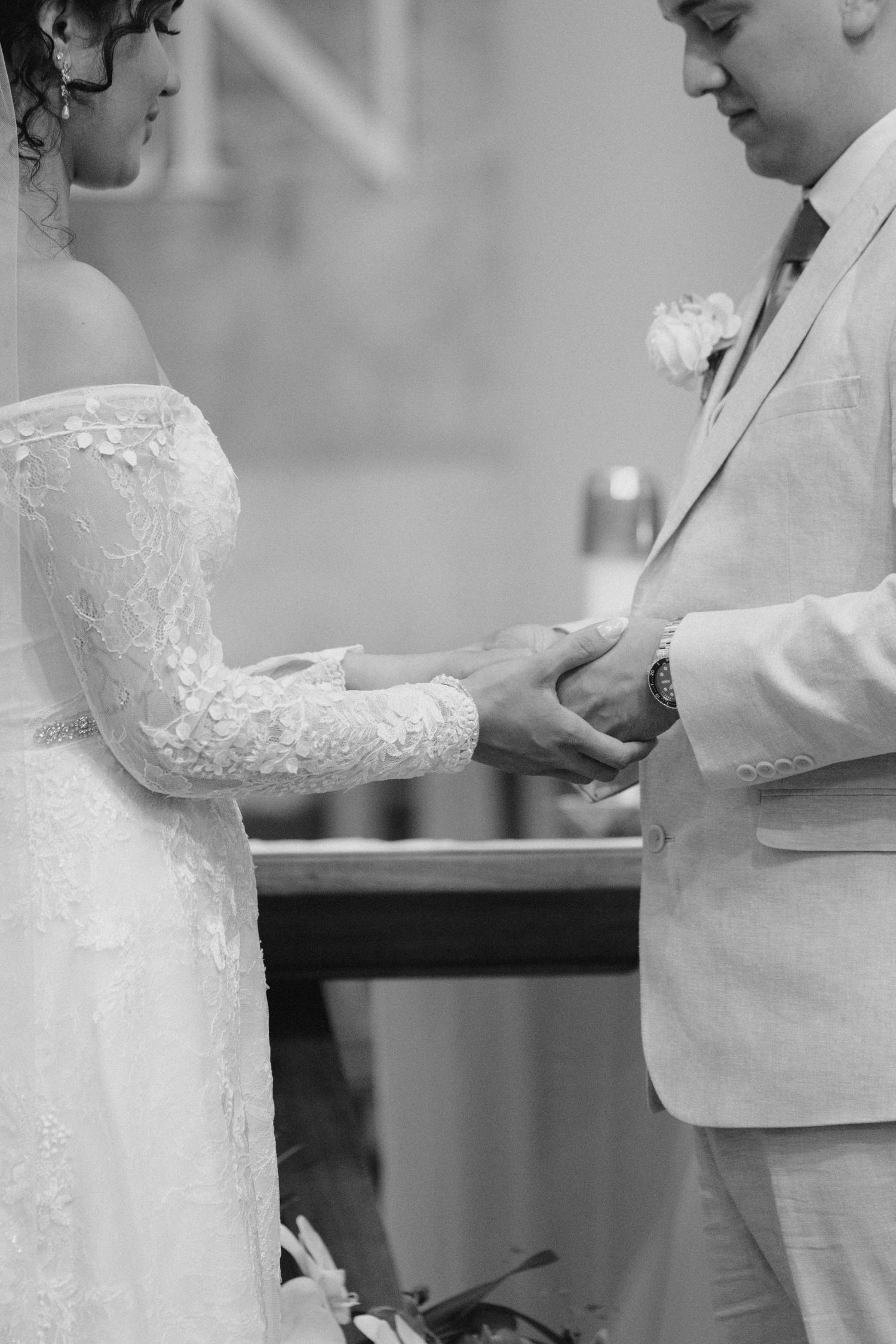 Black and white photo of a touching wedding ceremony moment as a couple exchanges rings during their intimate ceremony.