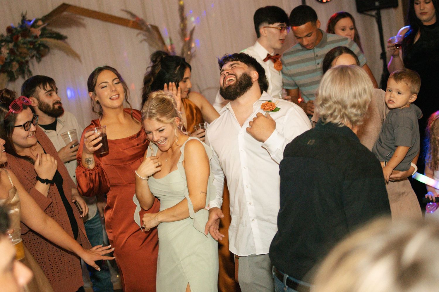 Wedding guests dancing and celebrating joyfully on the dance floor during a lively wedding reception party.