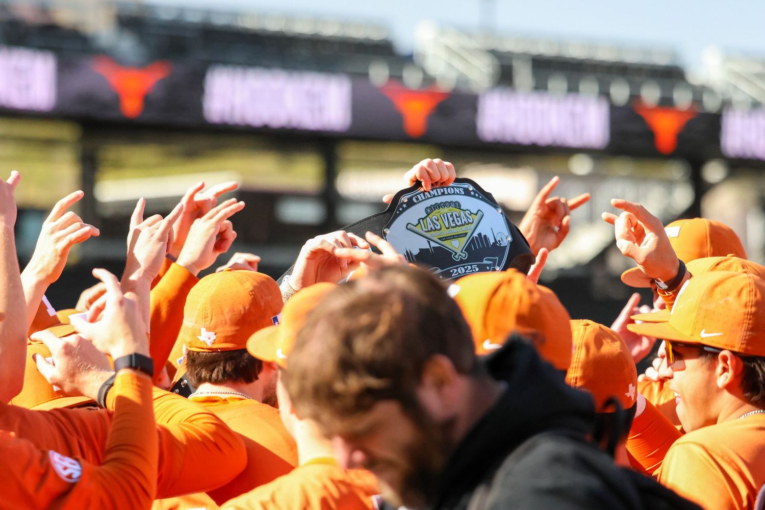 College football fans in orange team gear celebrate during a game at a stadium.