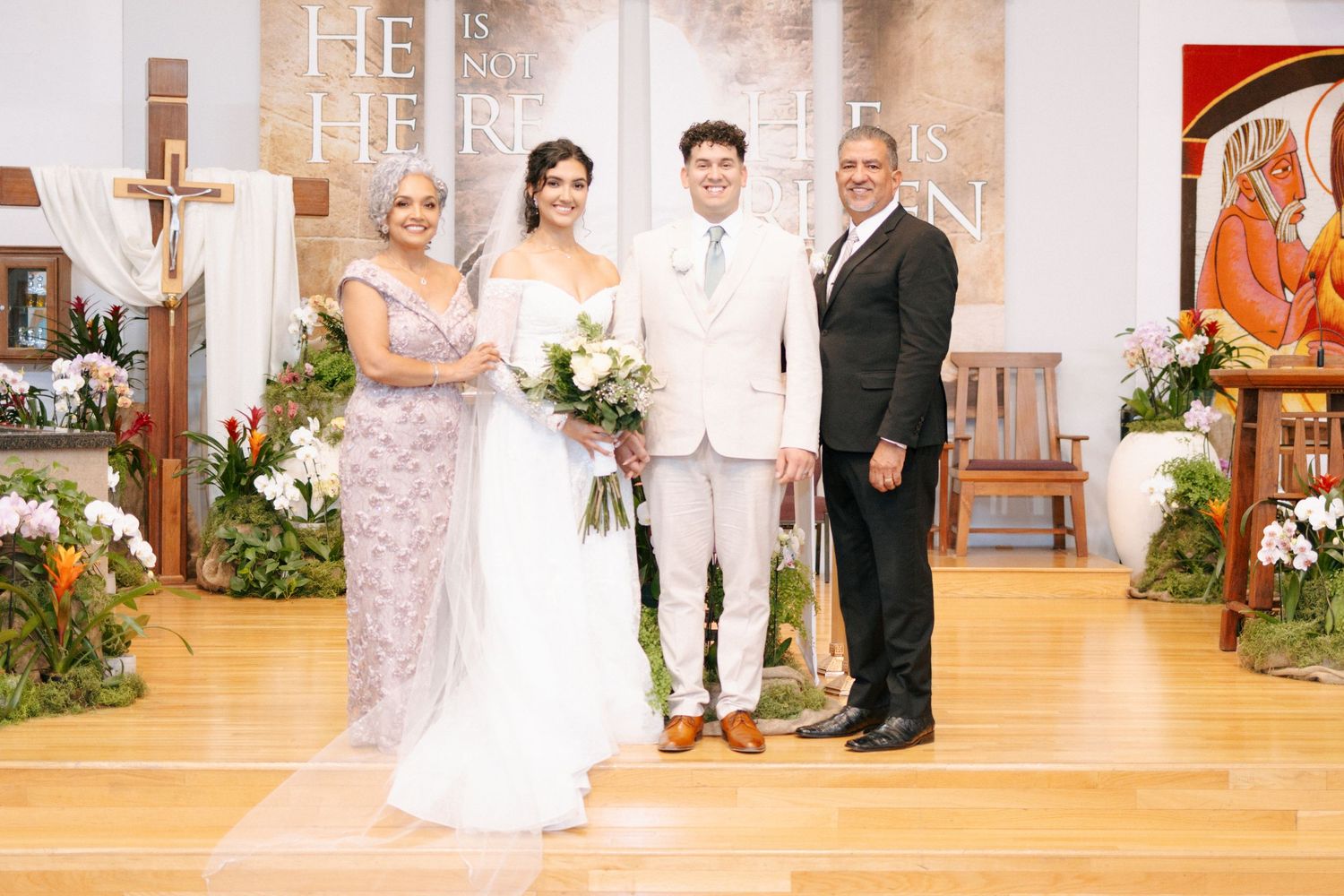 People stand in an elegant church decorated with floral arrangements for a wedding ceremony.