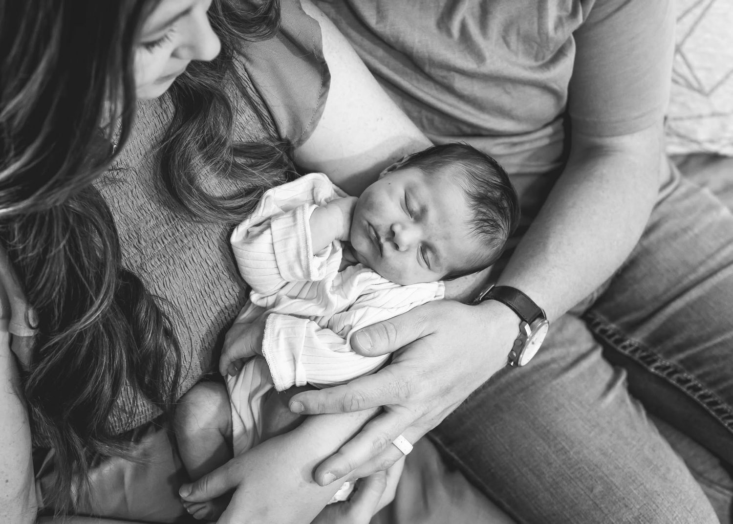Black and white photo of parents cradling sleeping newborn baby.
