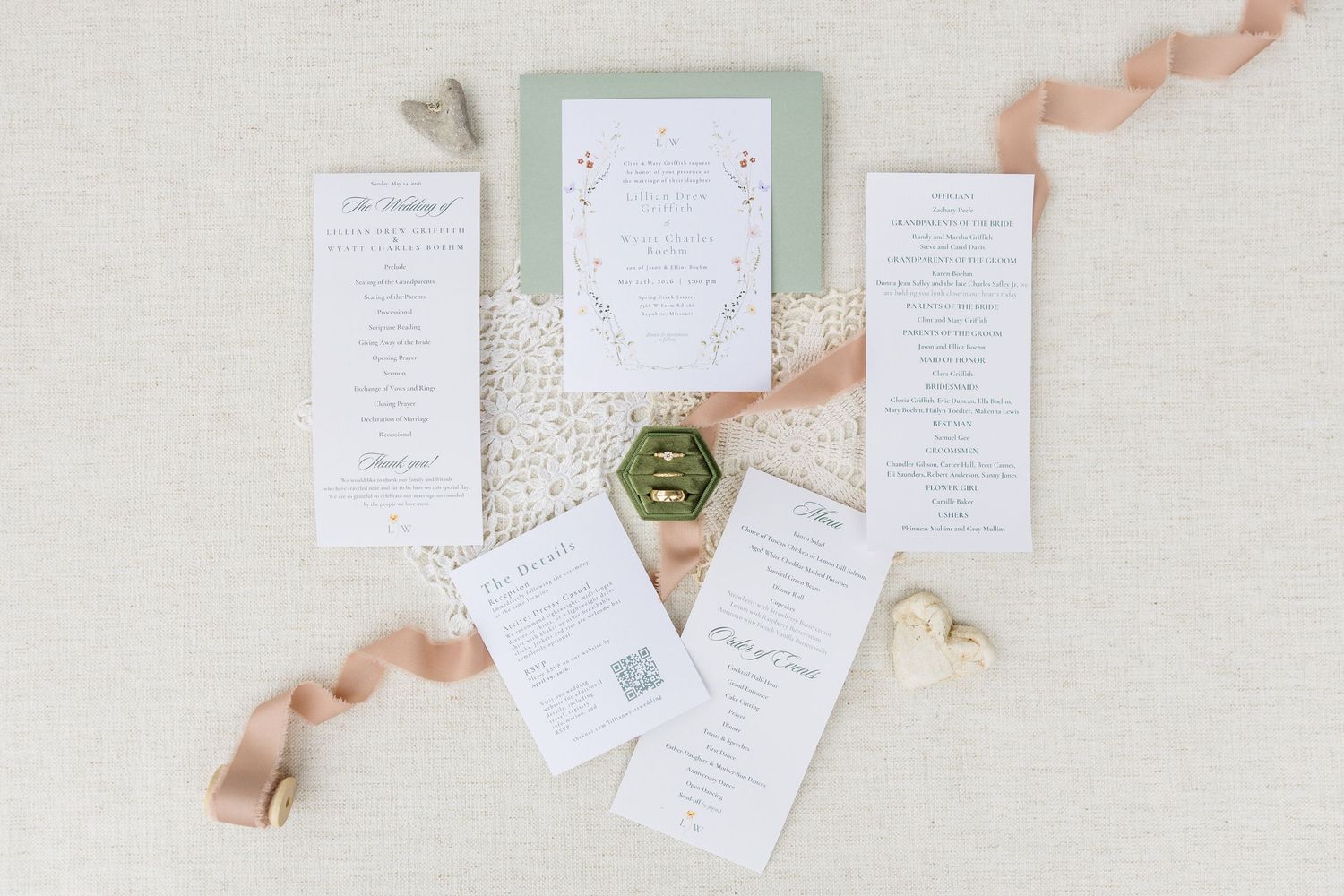 Elegant wedding stationery suite with sage green invite, menus, and programs arranged with ribbon and ring box.