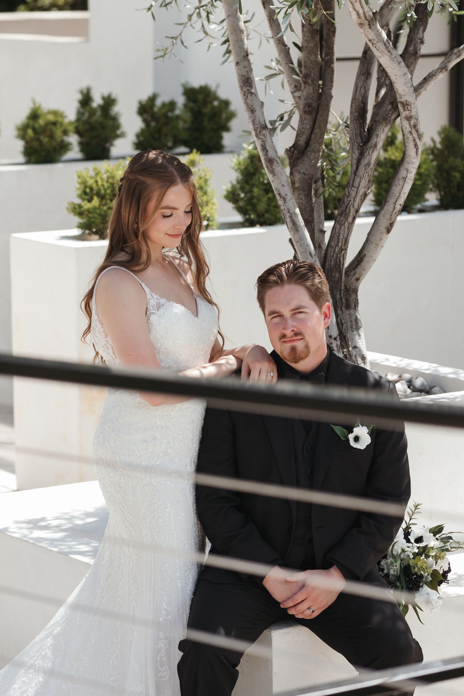 A candid wedding moment captured through decorative railings with the couple sharing a tender exchange.