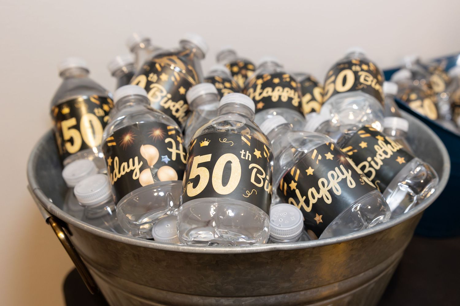 Decorative gold and clear balloons with '50' printed on them chilling in metal ice bucket.
