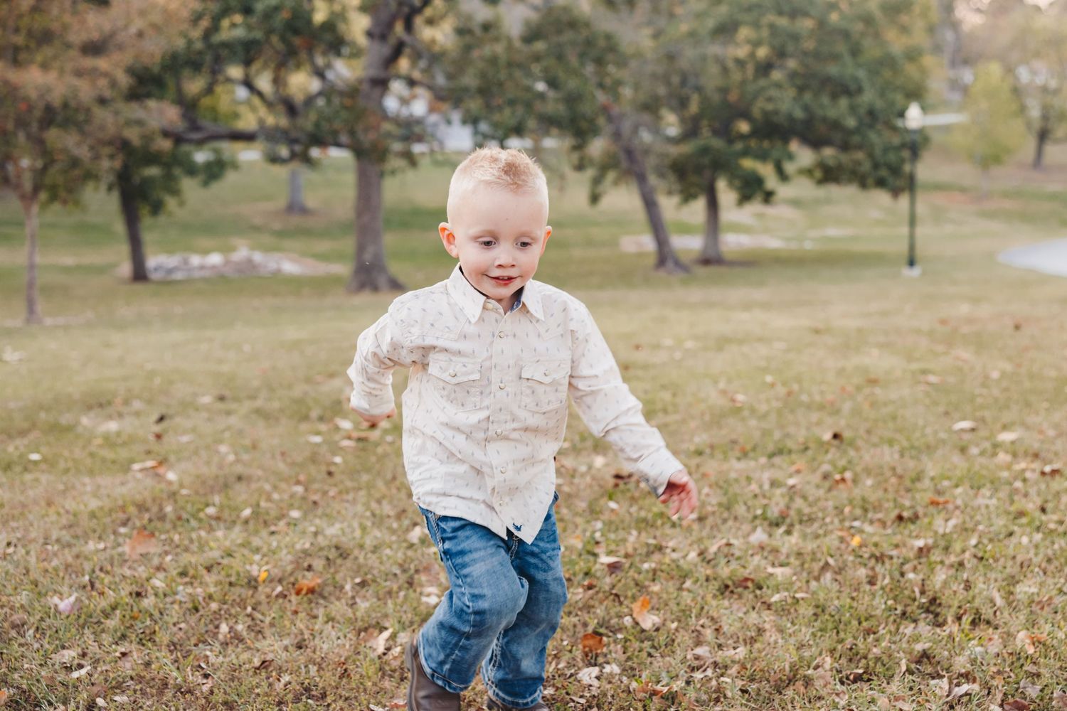 Child in light colored shirt and jeans runs through autumn field.