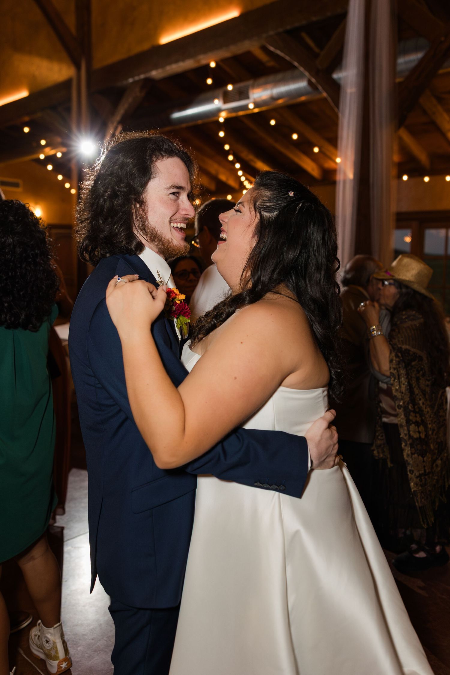 A romantic dance moment captured at an indoor wedding reception with warm lighting and wooden beams.