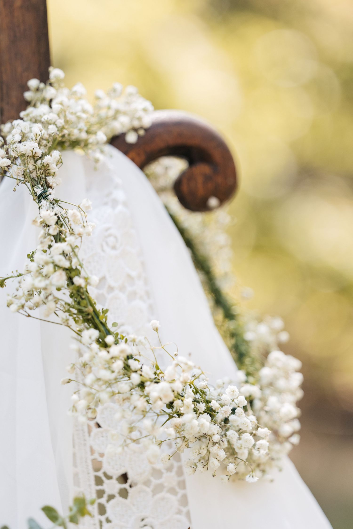 Delicate white baby's breath flowers adorning lace wedding dress detail.