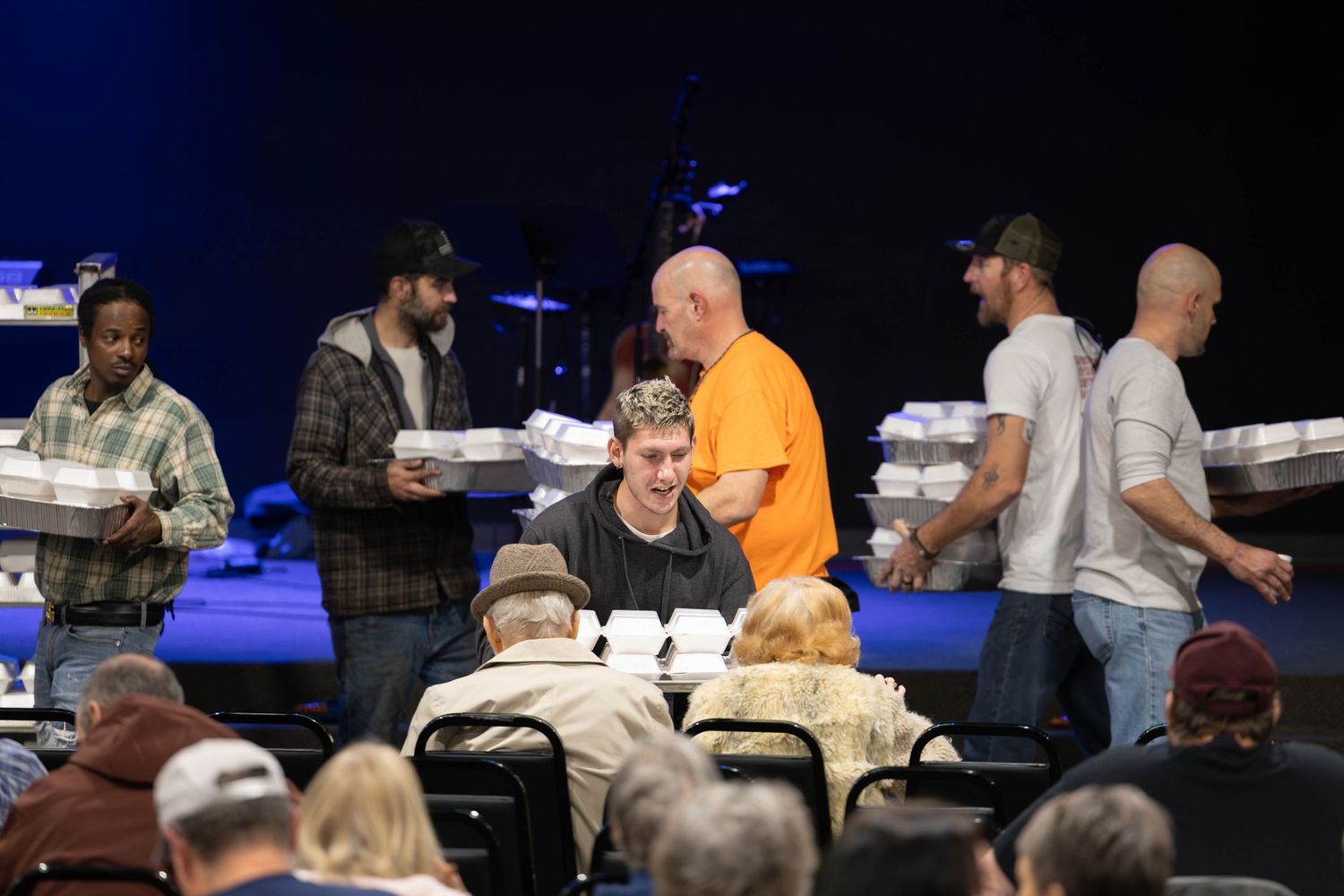 People serving food at tables during a community gathering or church event.