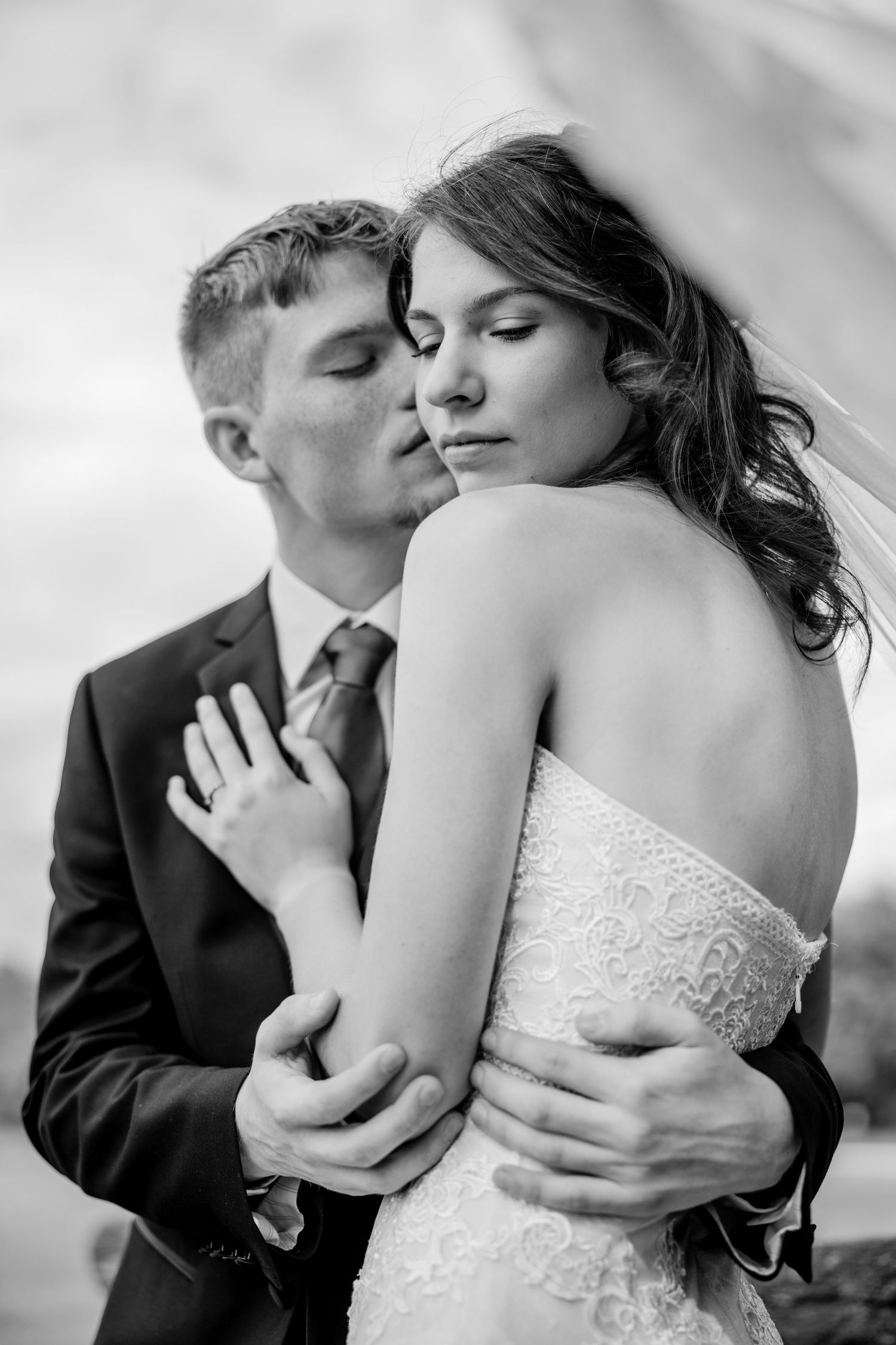 Romantic black and white portrait of couple embracing in wedding attire.