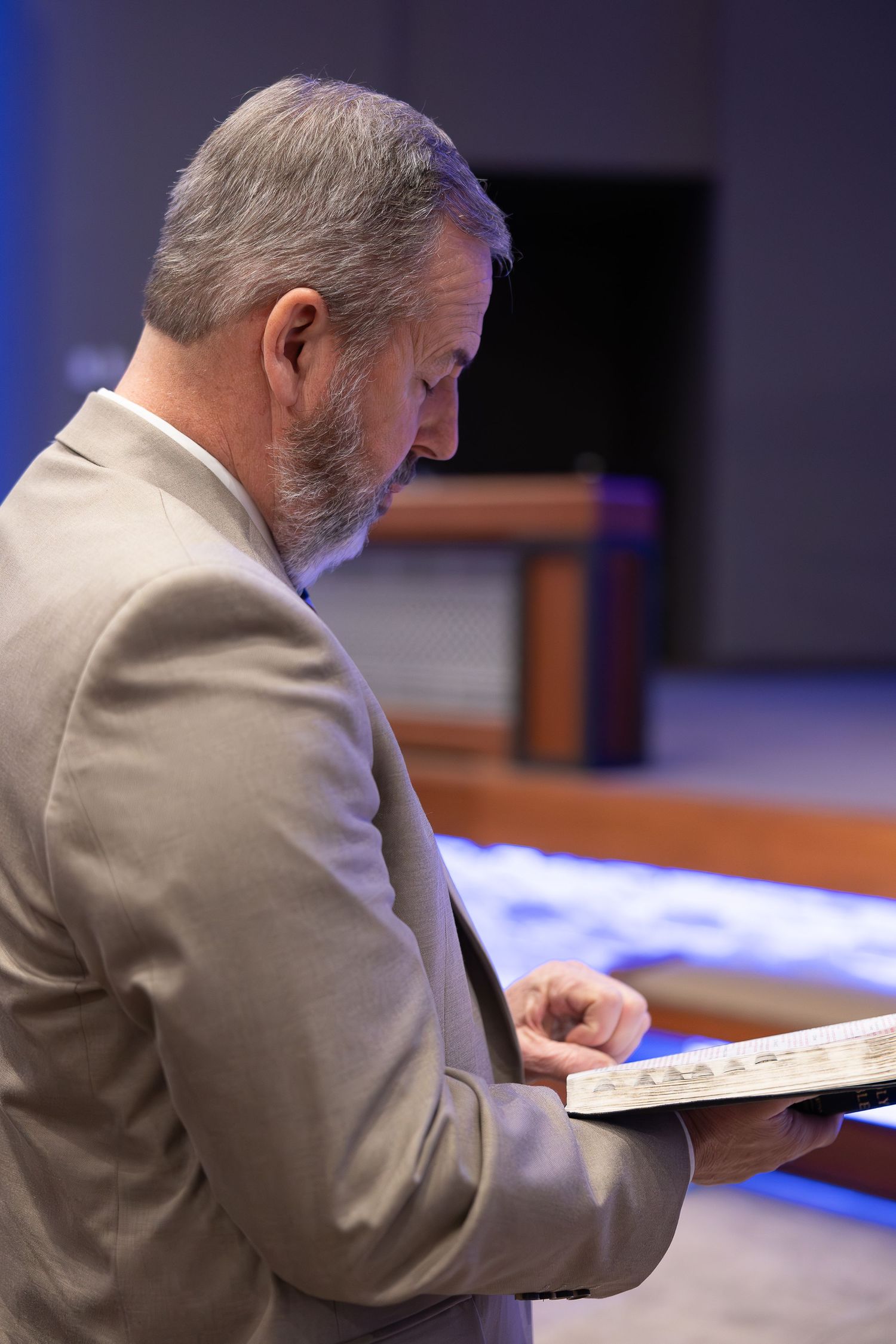 Side profile of person reading from open book in church setting.