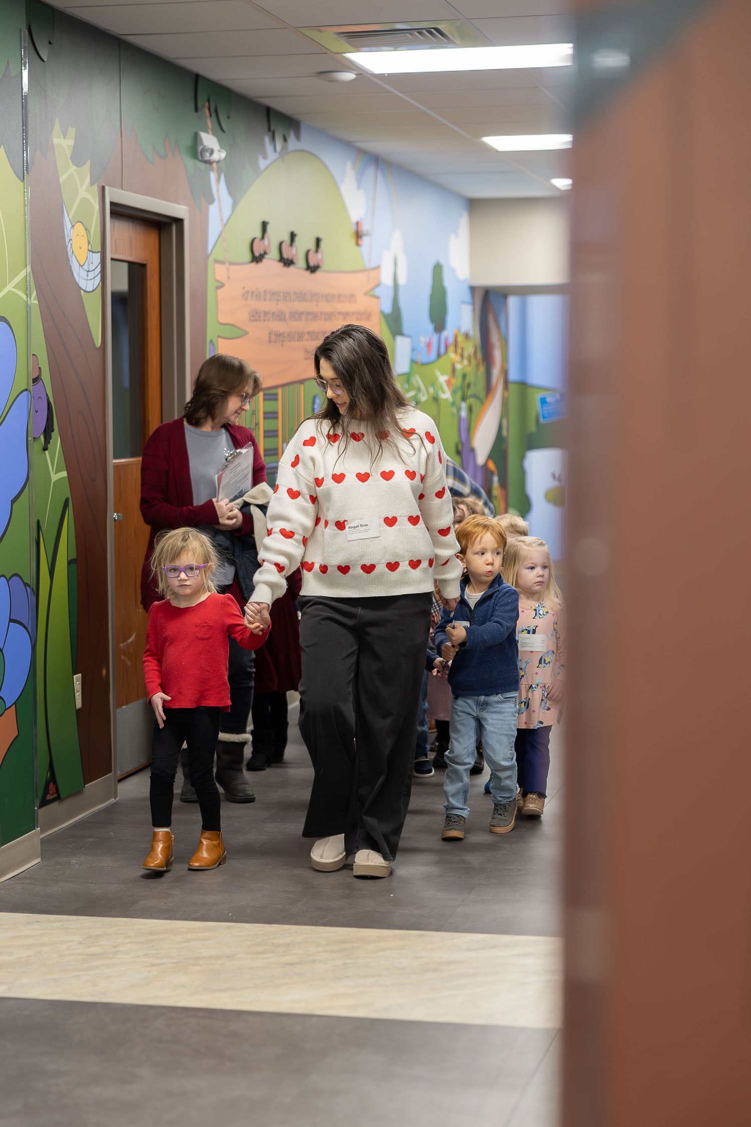 Group walking down hallway decorated with colorful garden-themed murals.