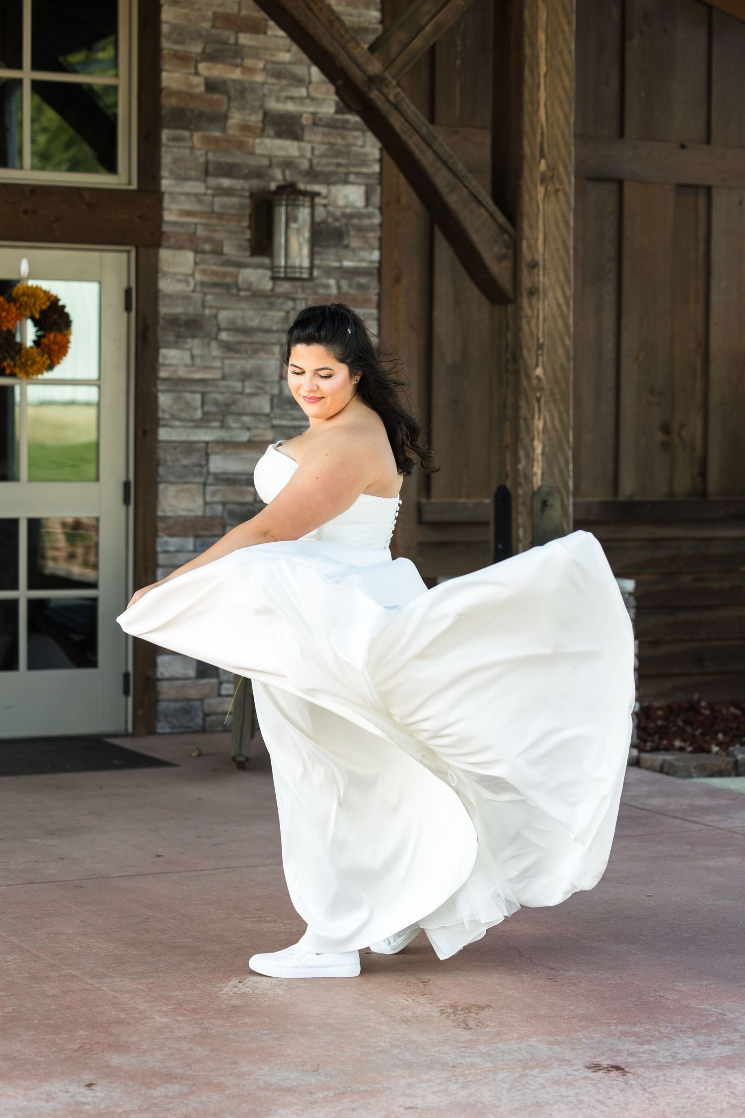 A flowing white wedding dress twirls elegantly on a stone porch with autumn decorations.