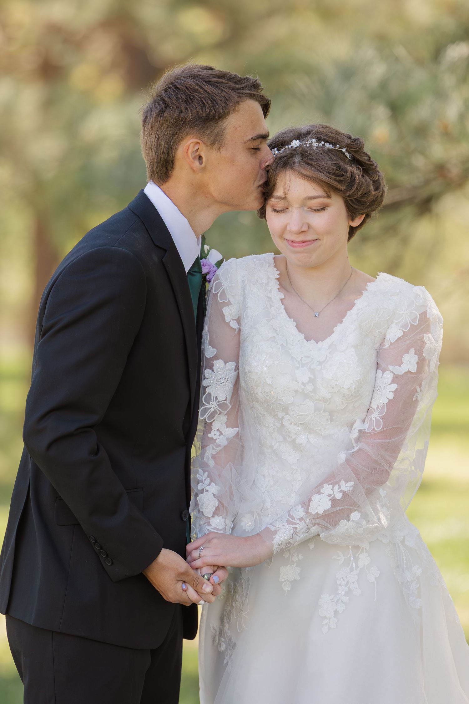 A tender moment between newlyweds outdoors as they embrace in romantic wedding day portraits.