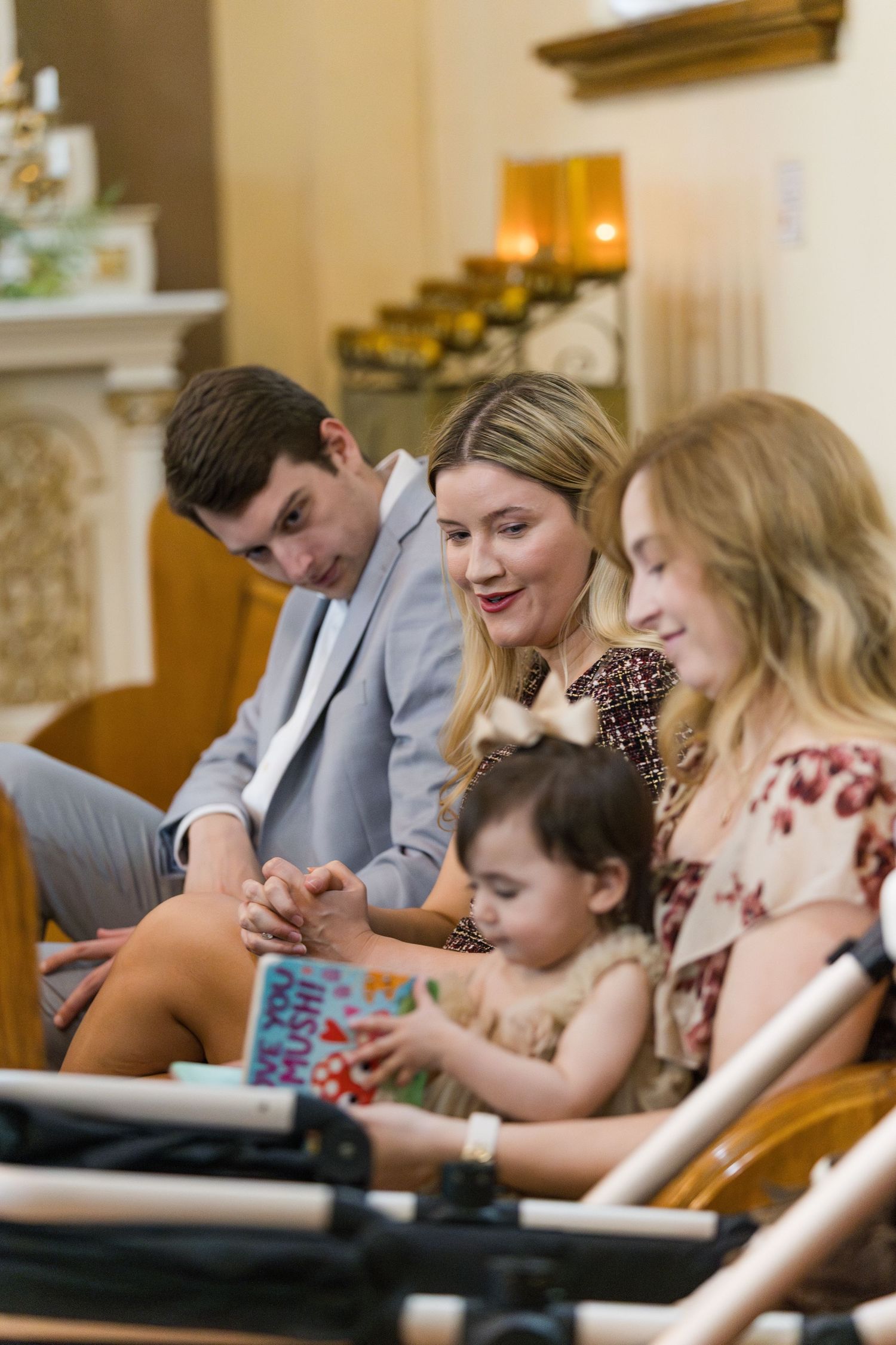 Family with toddler sits together in church pew during wedding ceremony reading program.