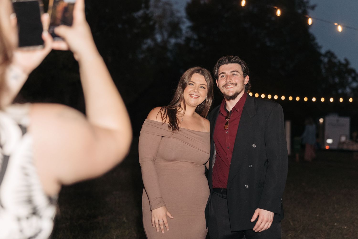 Casual evening portrait being captured under romantic string light decorations.