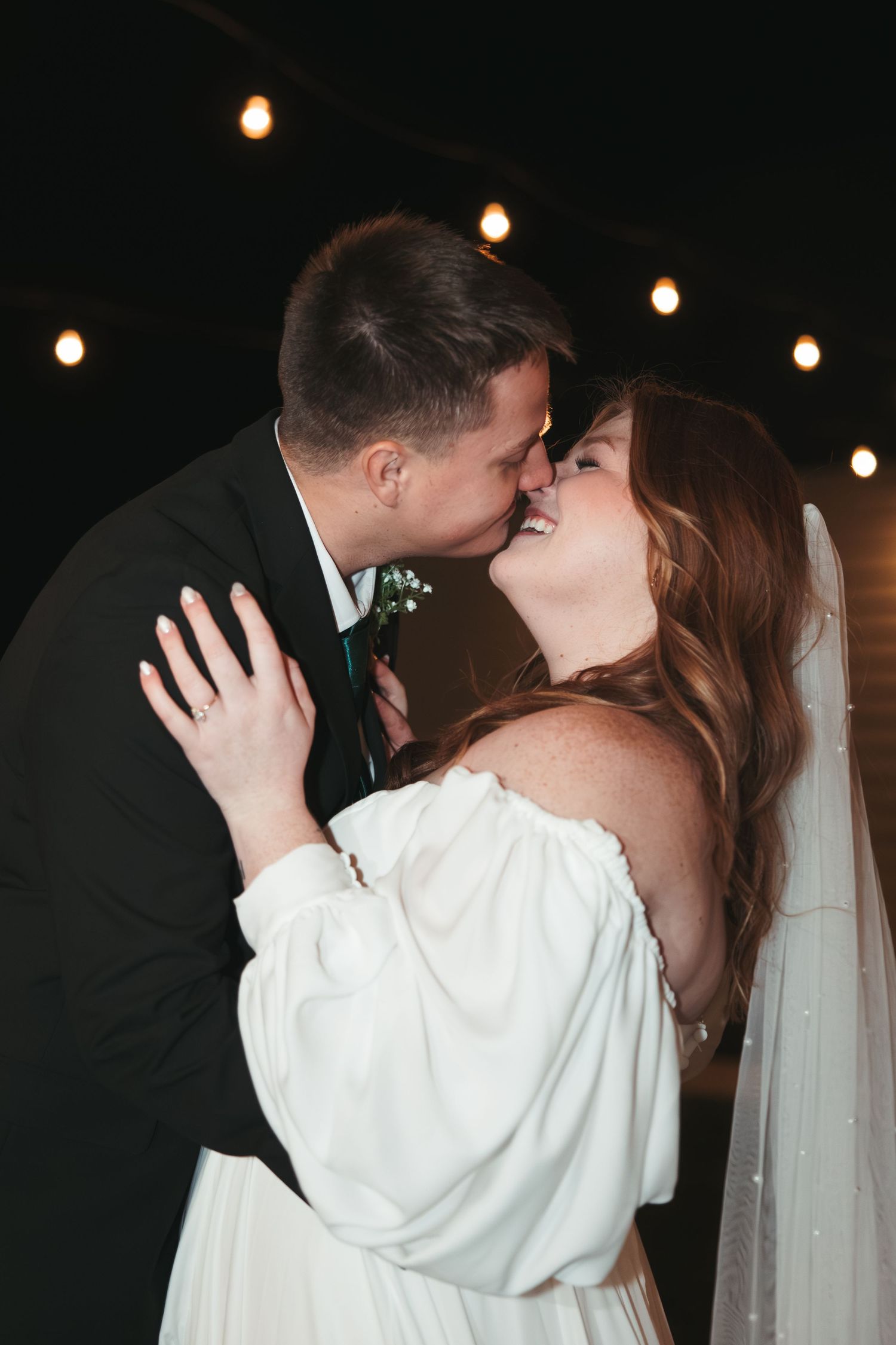 A romantic moment captured at night with string lights creating a magical atmosphere.