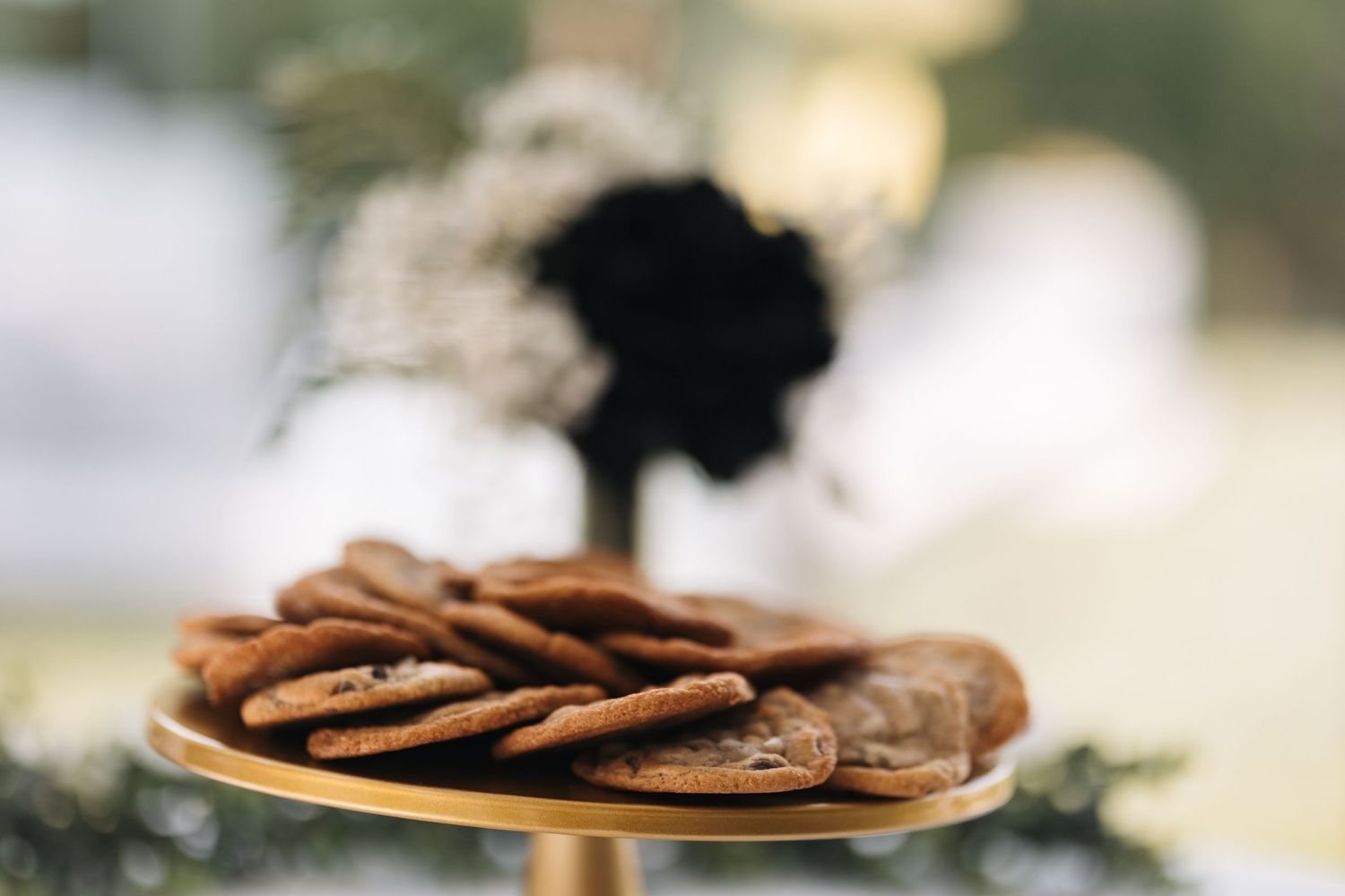 Plate of chocolate cookies on gold stand with soft focus background.