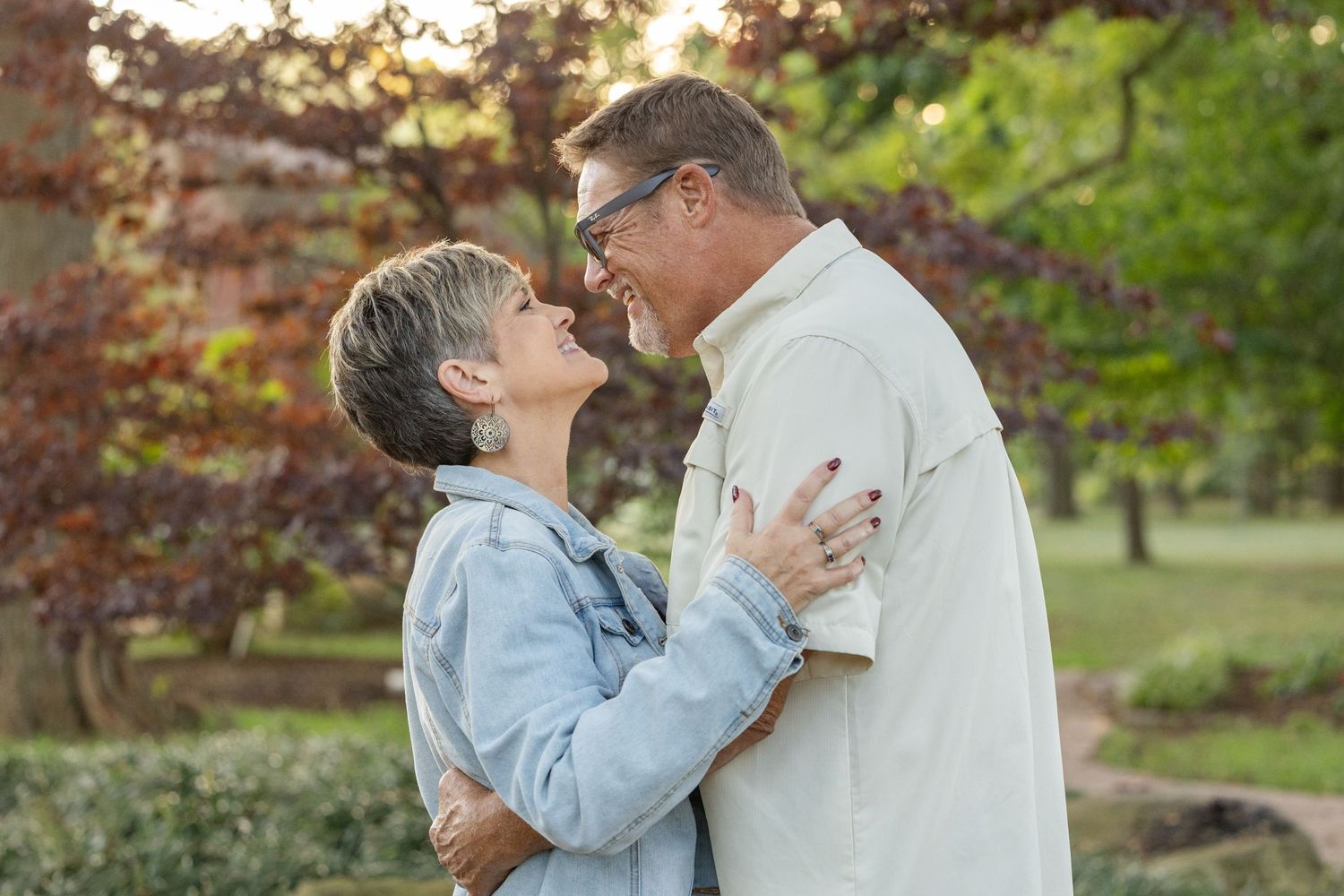Affectionate senior couple embracing outdoors in autumn garden setting.