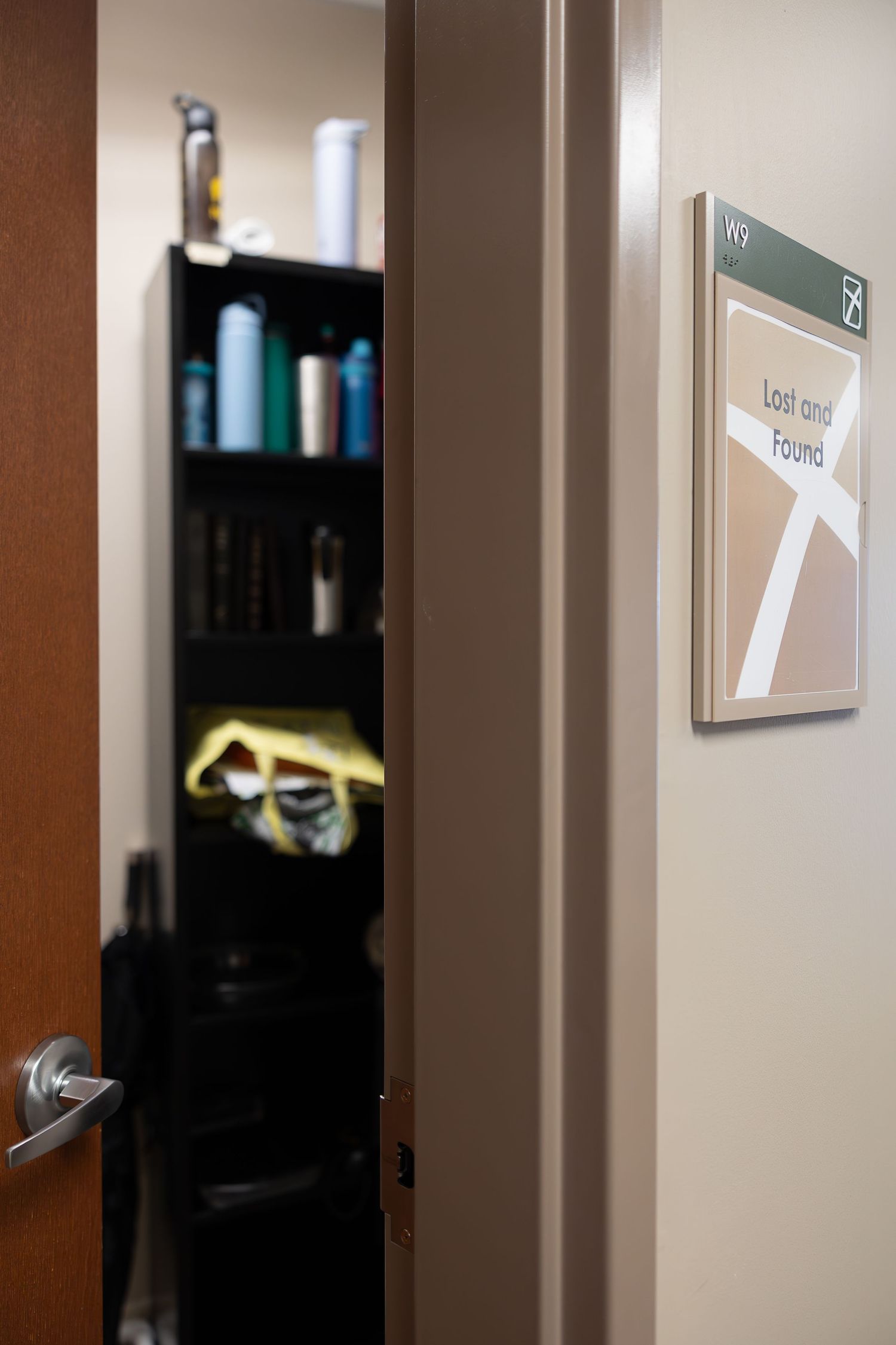 A glimpse into a supply closet with shelves of bottles and a directional sign mounted on the wall.