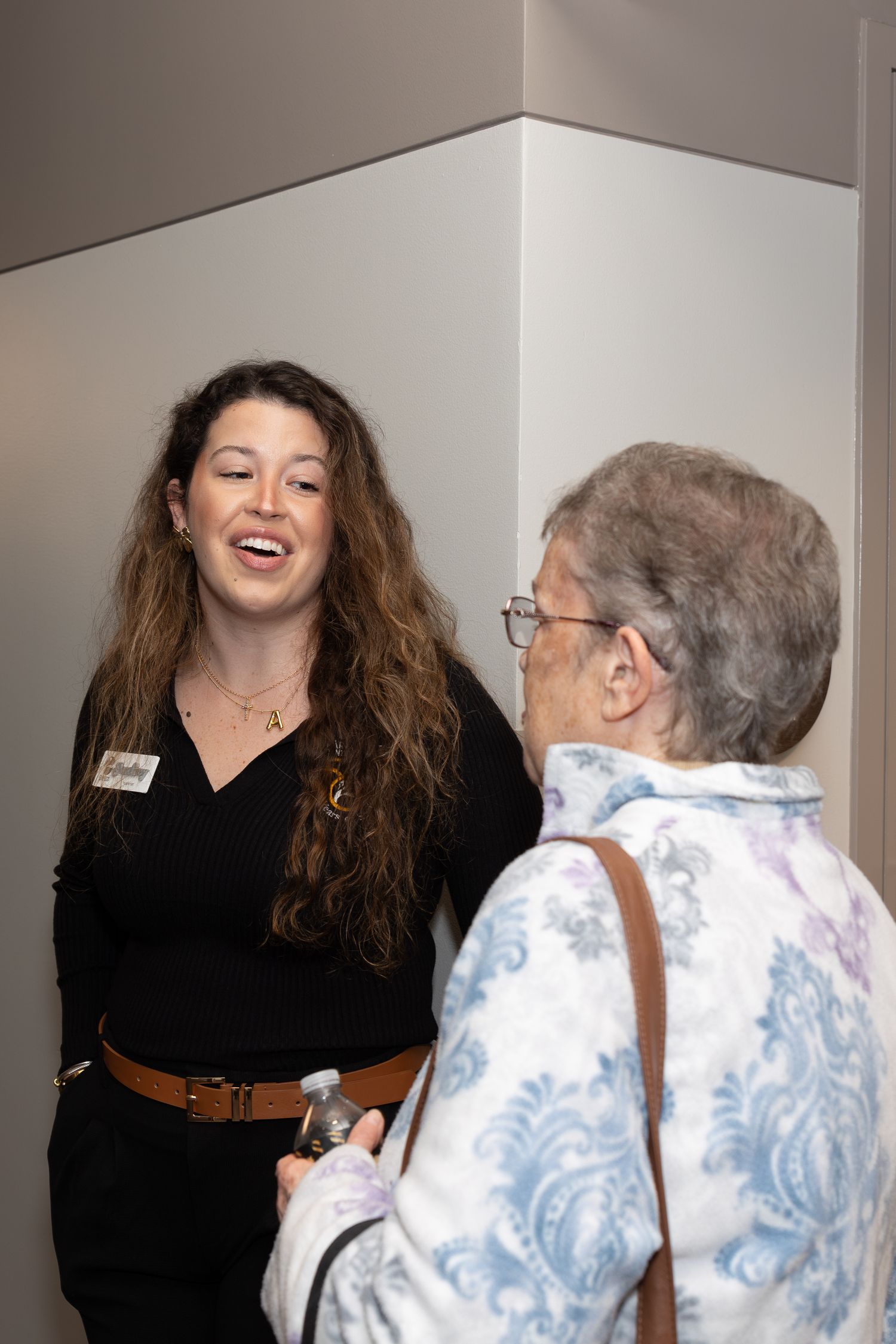 Two people engaged in cheerful conversation in an office hallway.