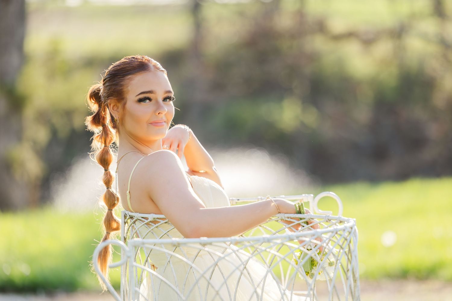 A person in a light dress poses outdoors with a white vintage bicycle at sunset.
