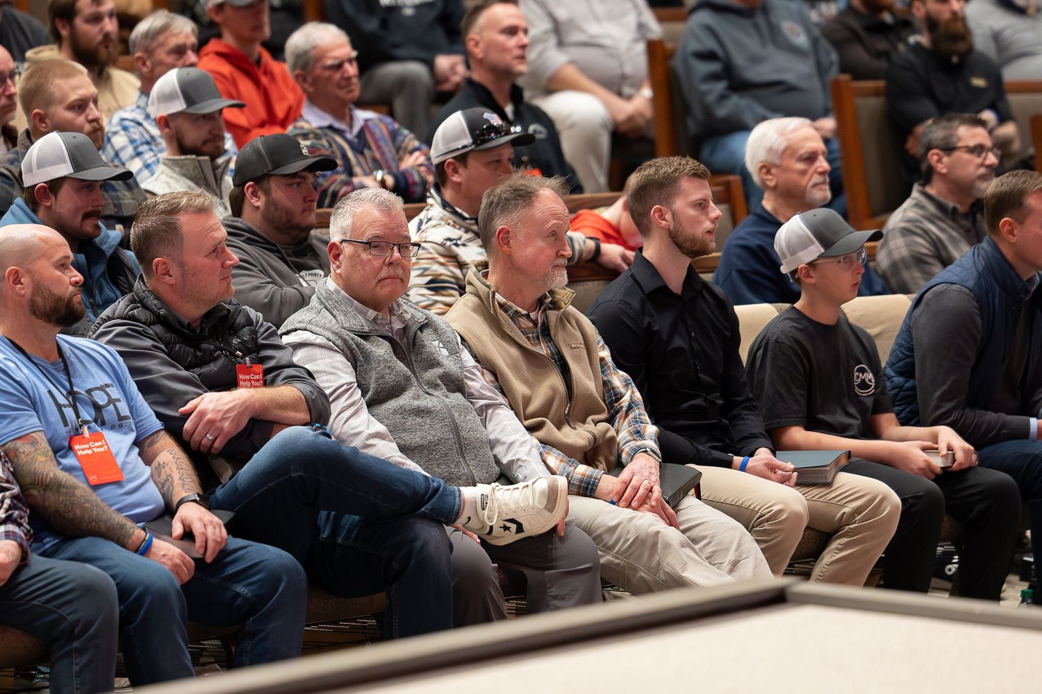 Audience members watching intently in stadium seating during an indoor sporting event.
