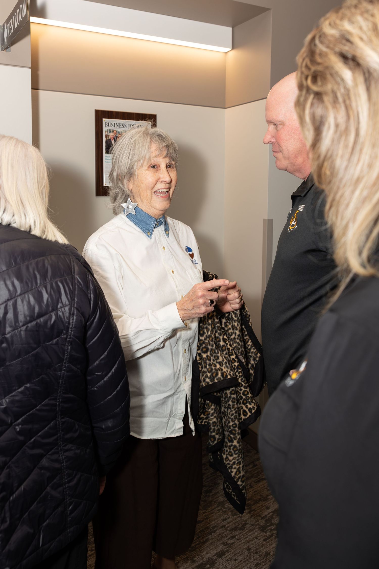 A group of people engaged in conversation in an office hallway.