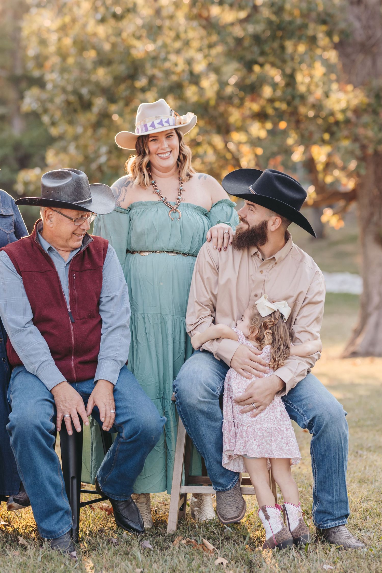A casual western-styled family portrait with cowboy hats and denim against an autumn backdrop.