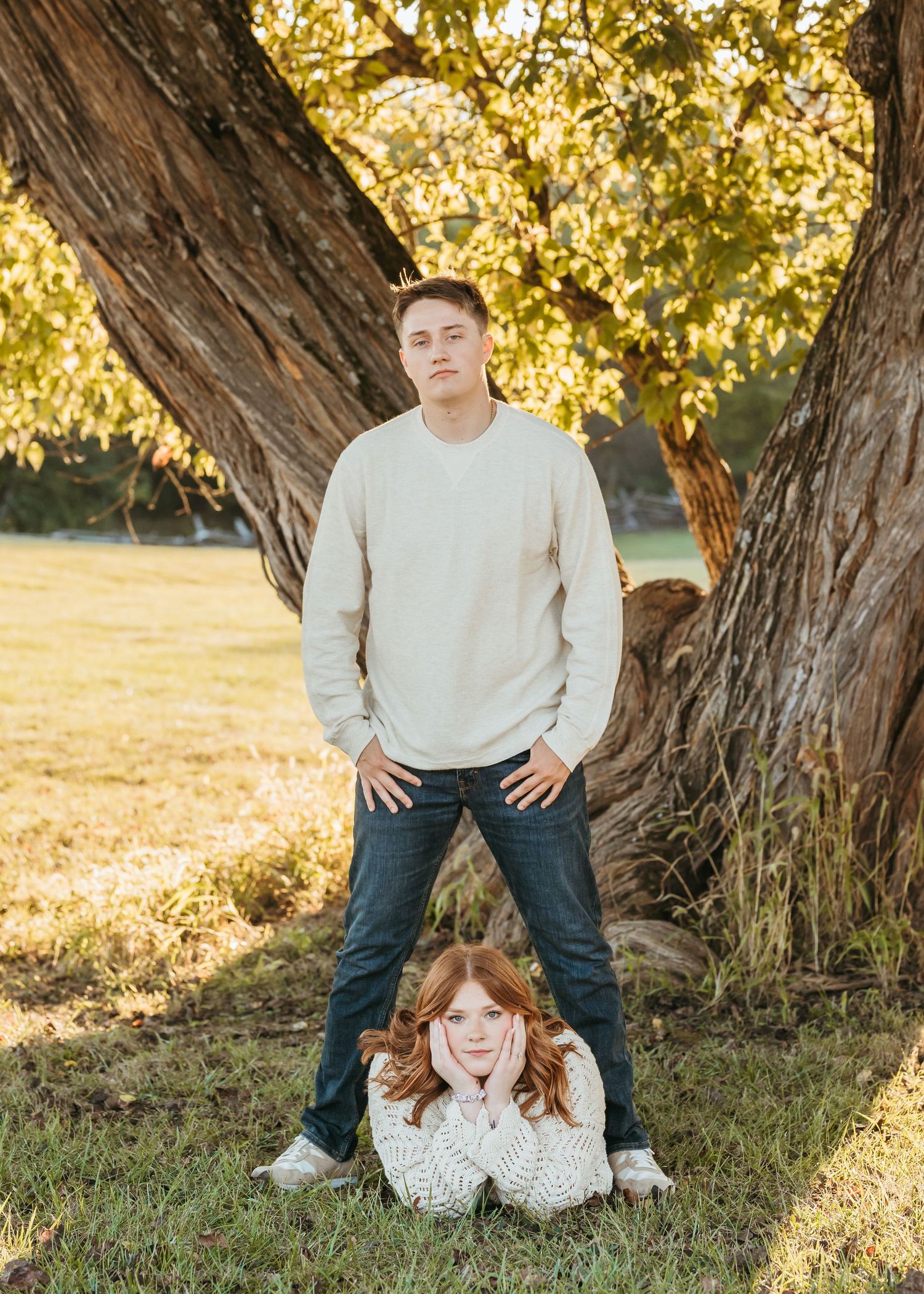 A creative portrait composition against a large tree trunk in warm evening light.