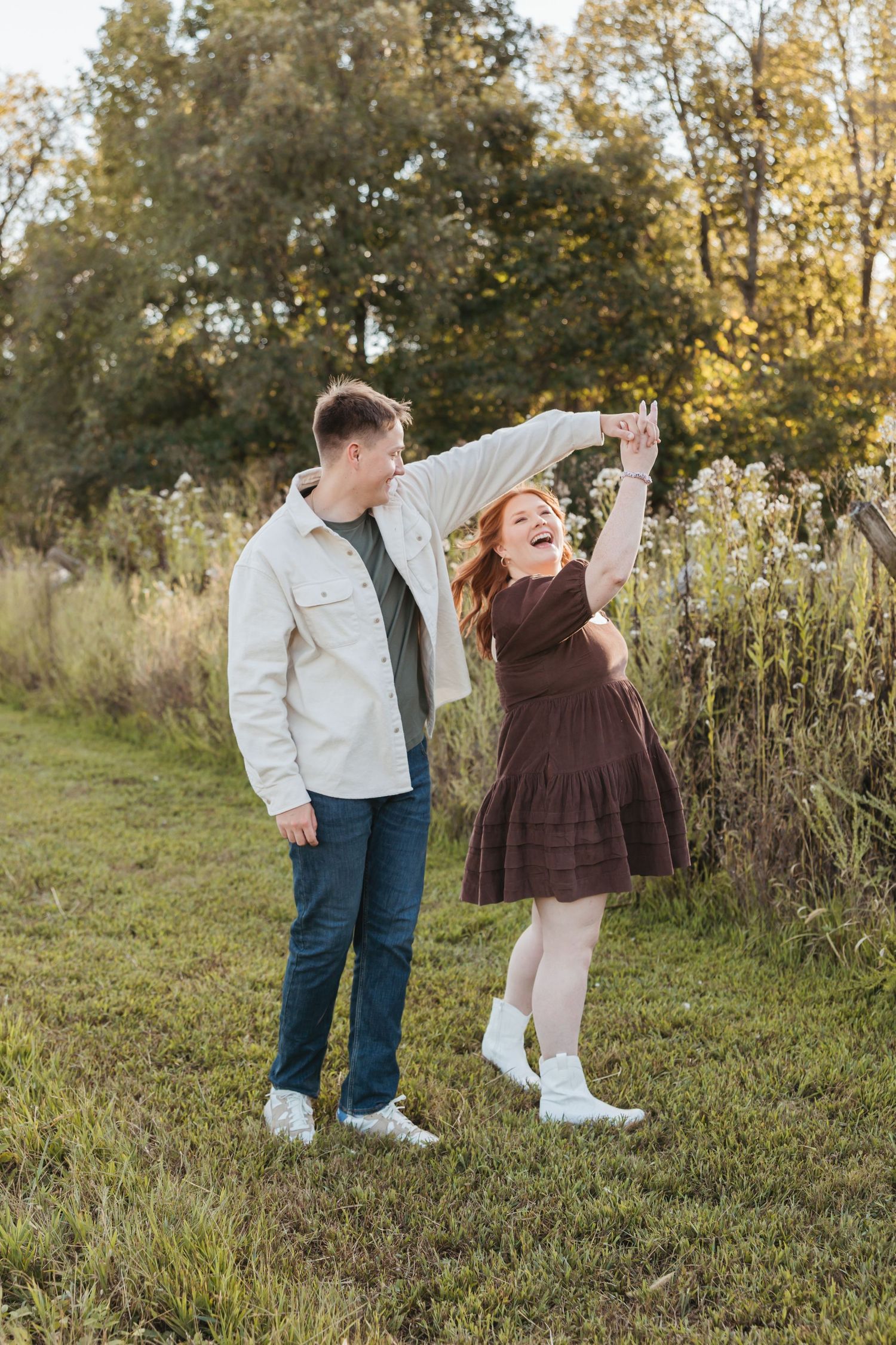 Playful dancing moment between a couple on a grassy path during golden hour.